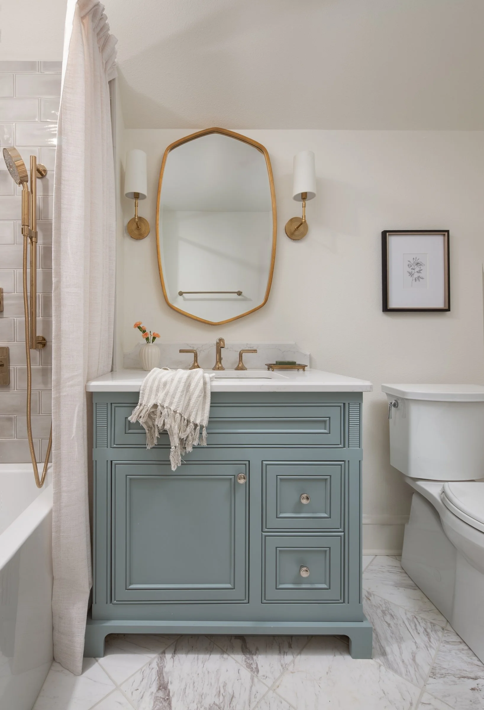 Whitefish Bay Tudor bathroom with blue vanity and brass mirror and sconces