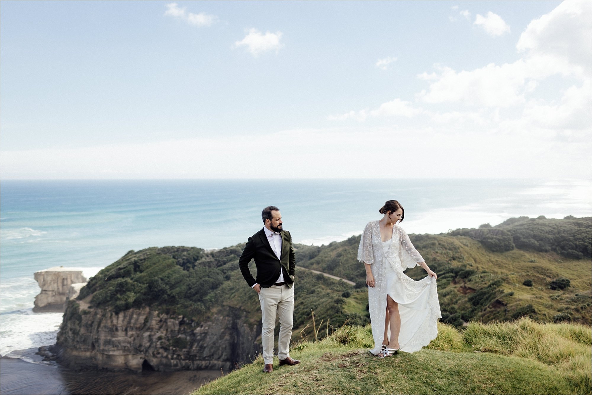 Bride checking her dress on a cliff top at Muriwai Beach
