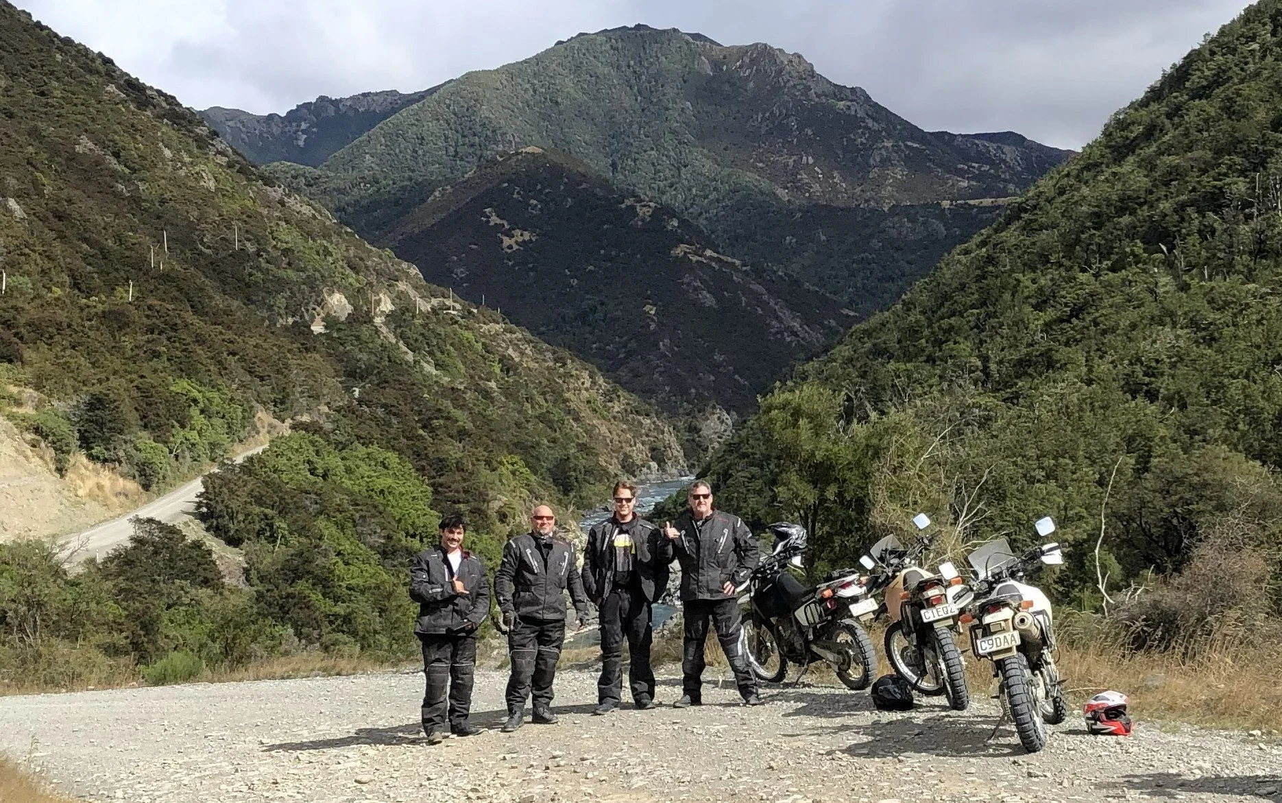 group of motorcyclists by a lake with snow-capped mountains