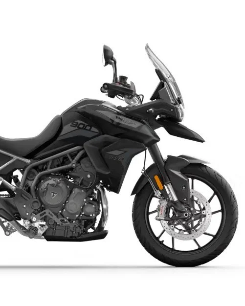 Black adventure motorcycle with windshield, mirror, and thick tires against a white background.
