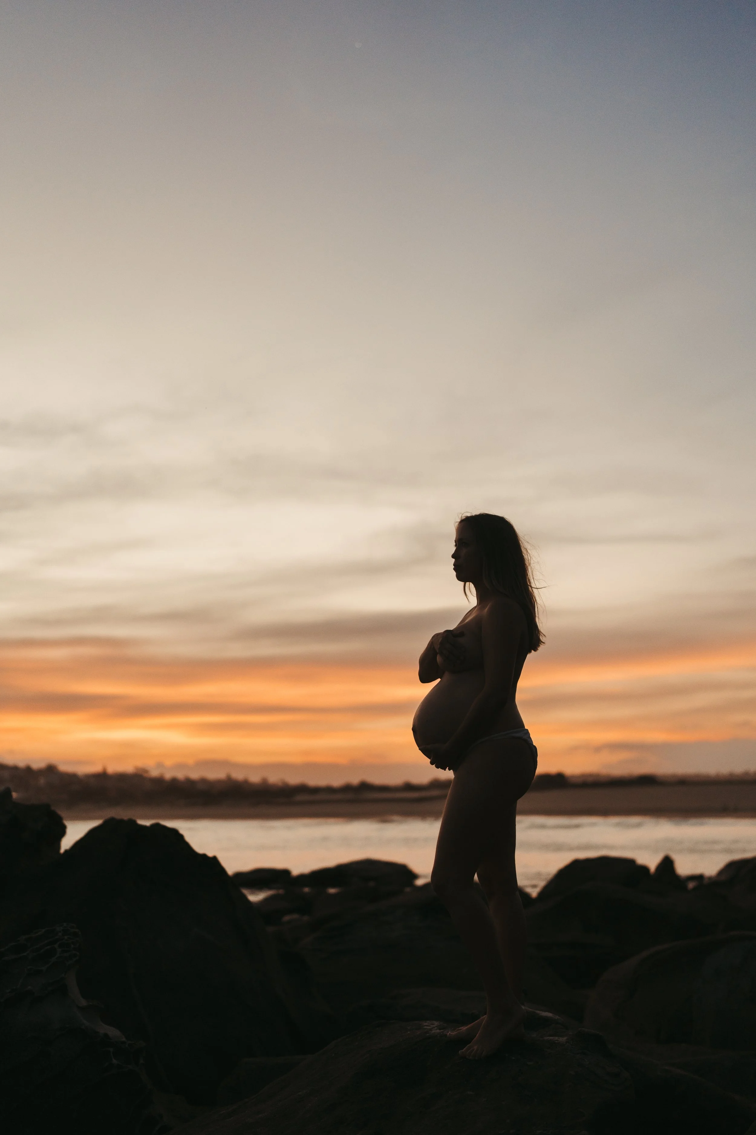 Silhouette of a pregnant woman at sunset on the beach in Sydney, during a maternity photography session