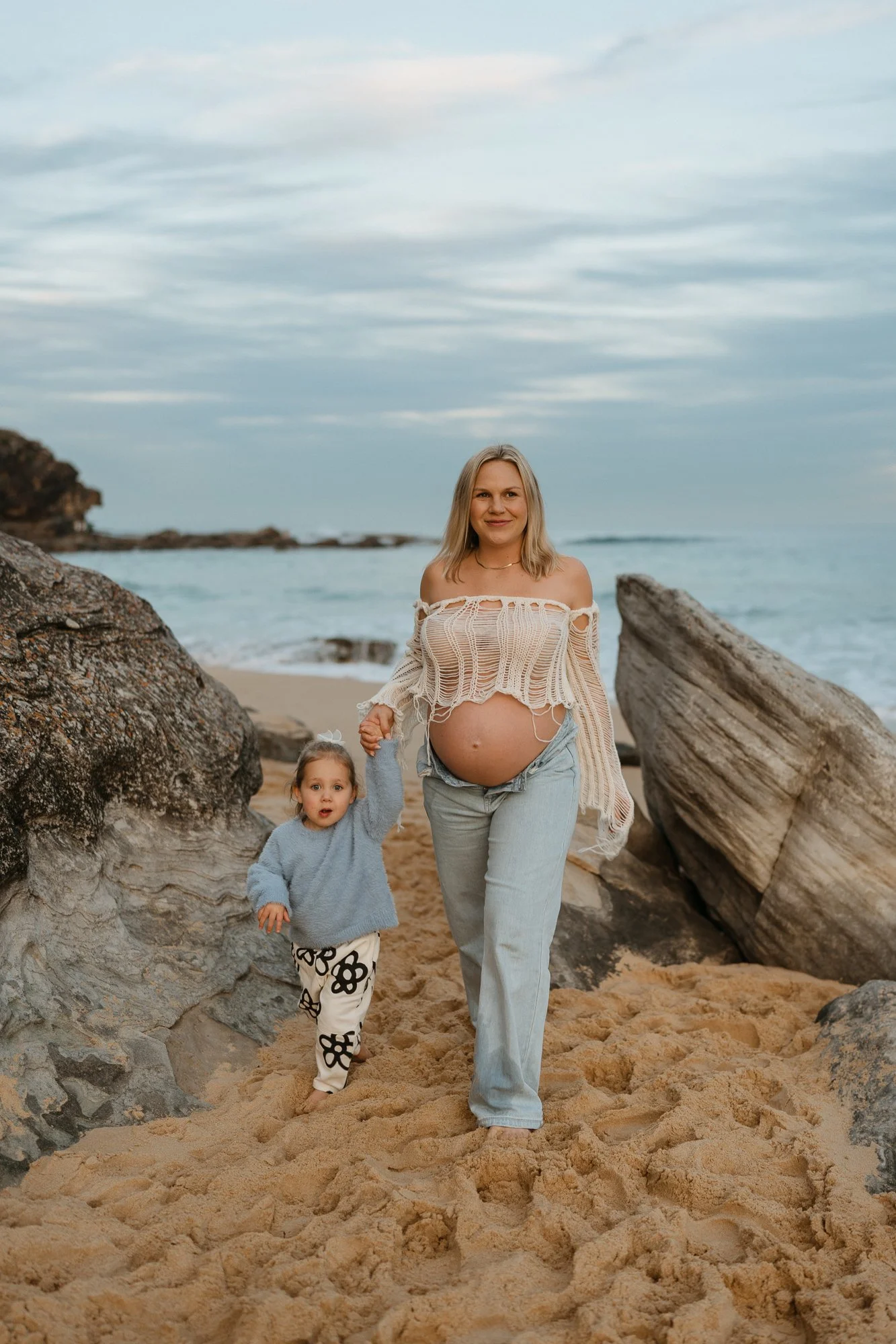 Pregnant woman and her little girl playing on the beach during a photography session at Curl Curl Beach