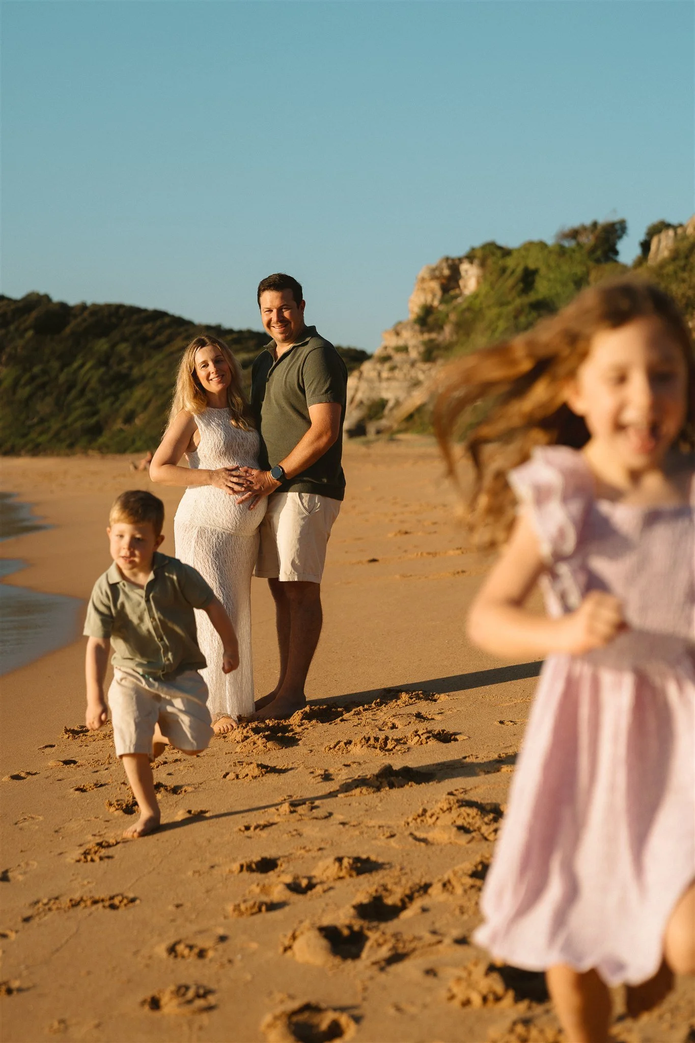A family with two young kids playing on Turimetta Beach during a family photography session | Sophie Smith Photography