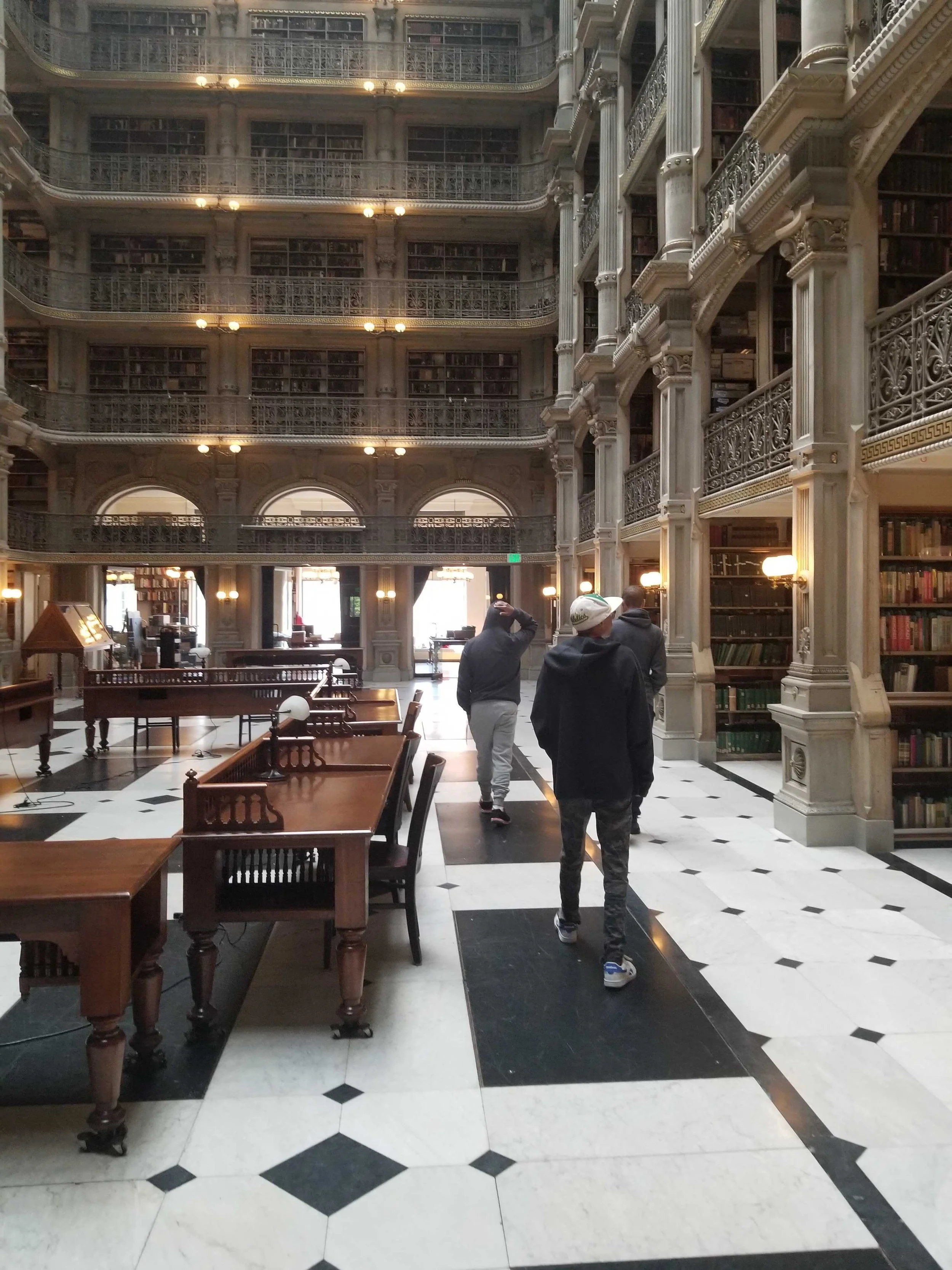 Three men walk through the George Peabody Library