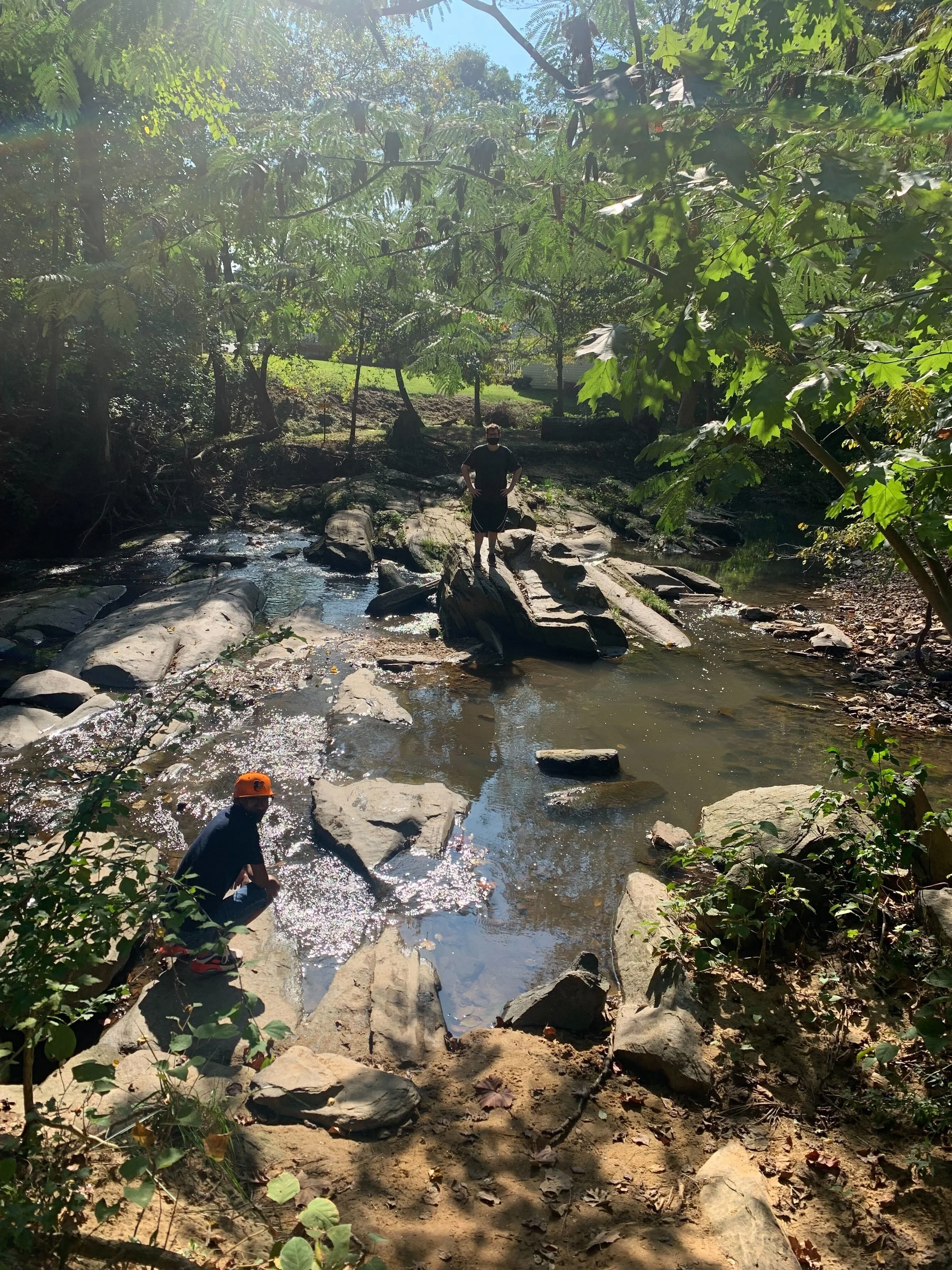 Man sits at the edge of a creek in the woods