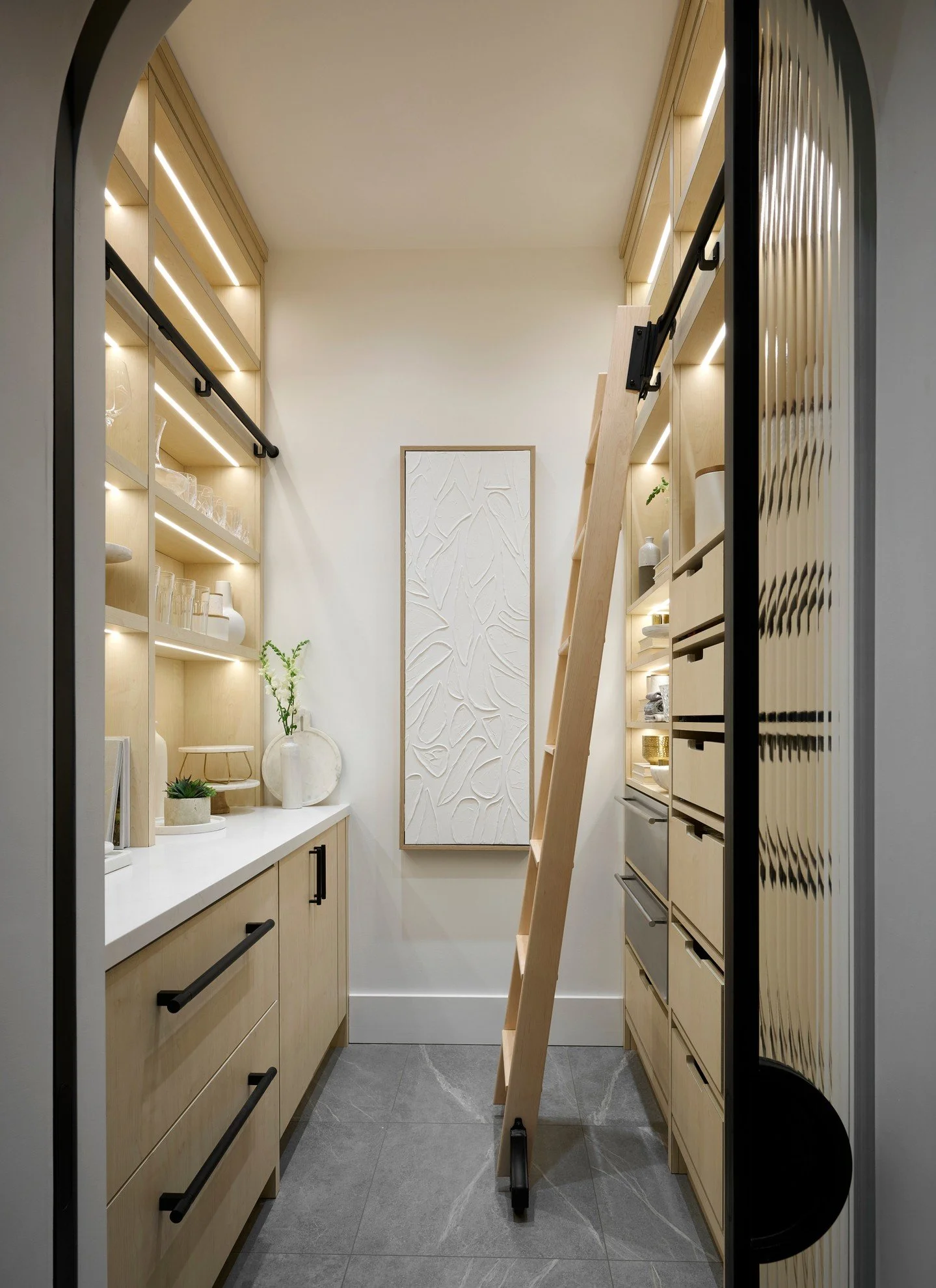 How gorgeous is this pantry we designed! 
Beautiful millwork with a library ladder that can be used on both sides. Built in fridge, ice maker, and warming drawers for entertaining. Storage shelves with integrated lighting. And a stunning pocket door 
