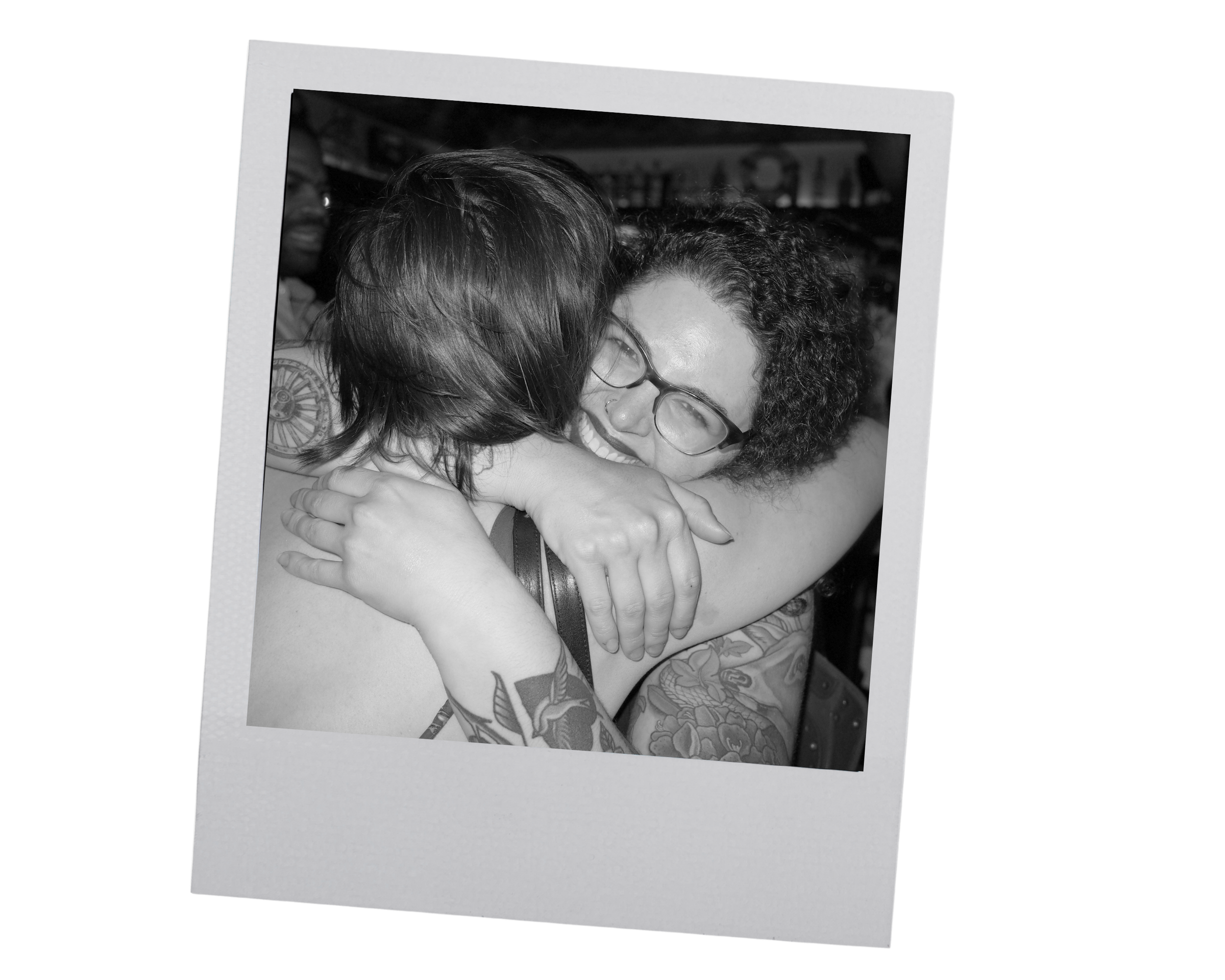 black and white poloroid of Meryl, somatic coach, giving a big hug and smiling at the camera