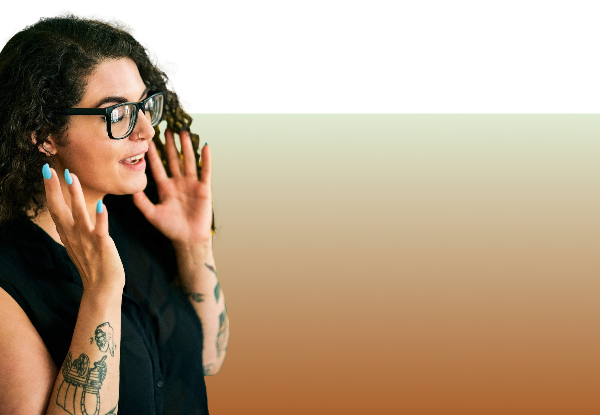 A woman with curly hair, glasses, blue nails, and tattoos, is talking or singing with her hands near her face.