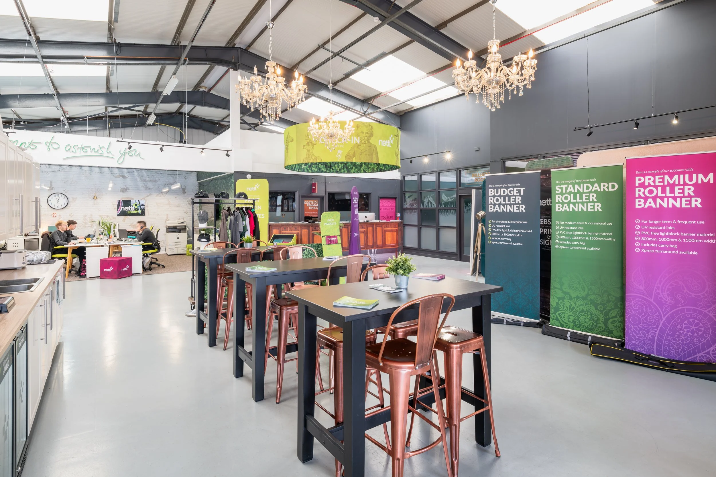 Open-plan creative studio office with branded roller banners, high tables, and modern interior design.