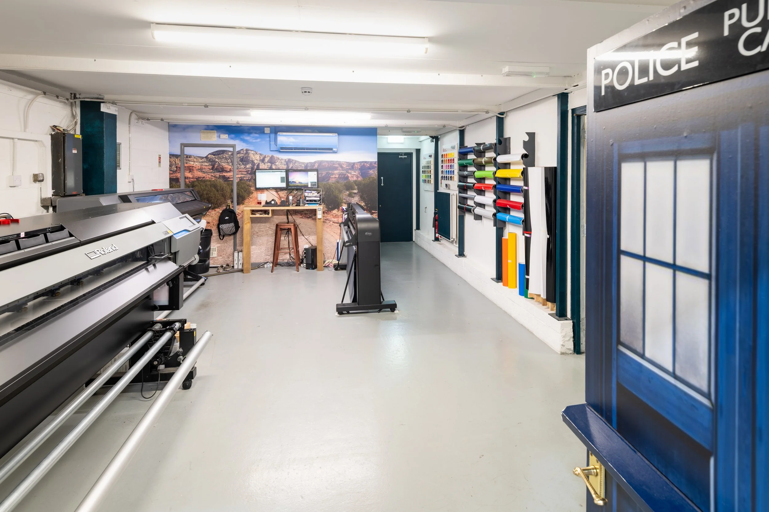 Professional vinyl printing and signage studio with wide-format printer and material samples on display.