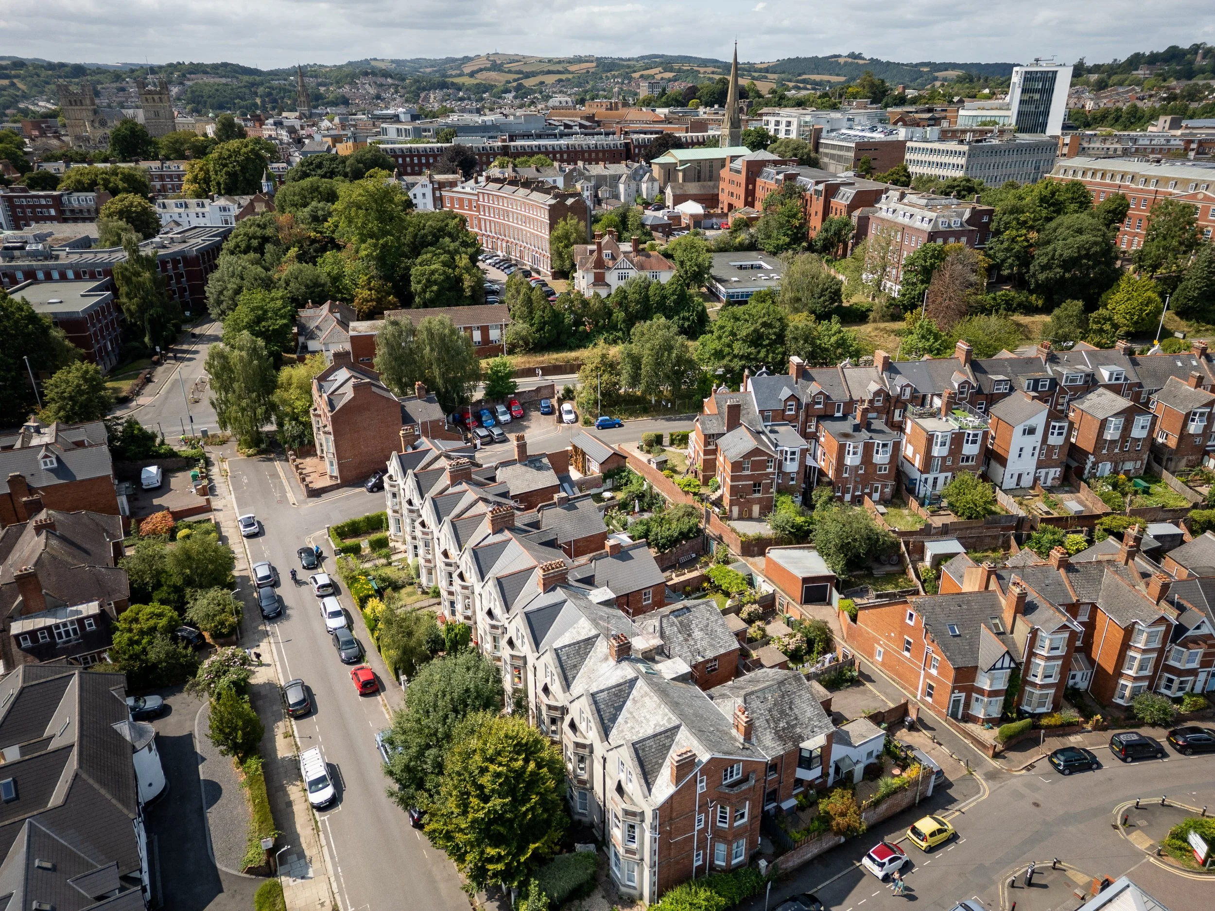 Drone photography of Exeter showing residential estates, terraced houses, and city skyline