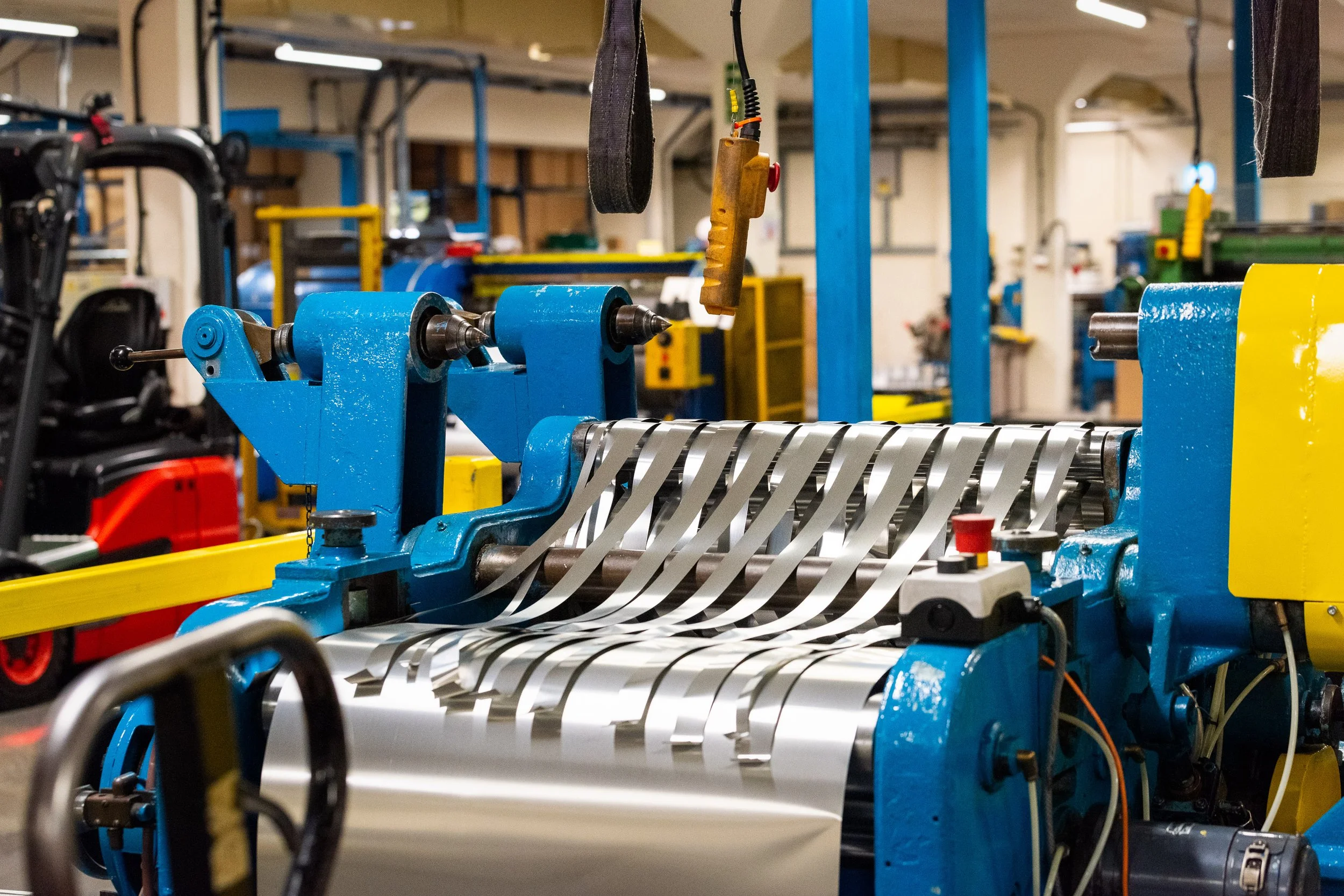 Industrial slitting machine cutting wide aluminium foil roll into narrow strips for commercial use.