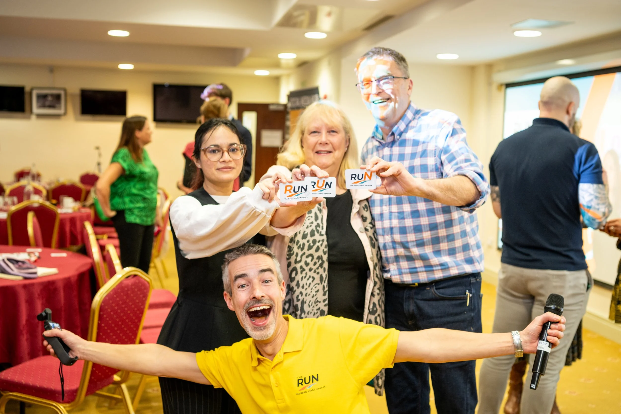 Group of people at a lively indoor event holding branded cards, captured in a last-minute event photography shoot for corporate functions, marketing and business promotion