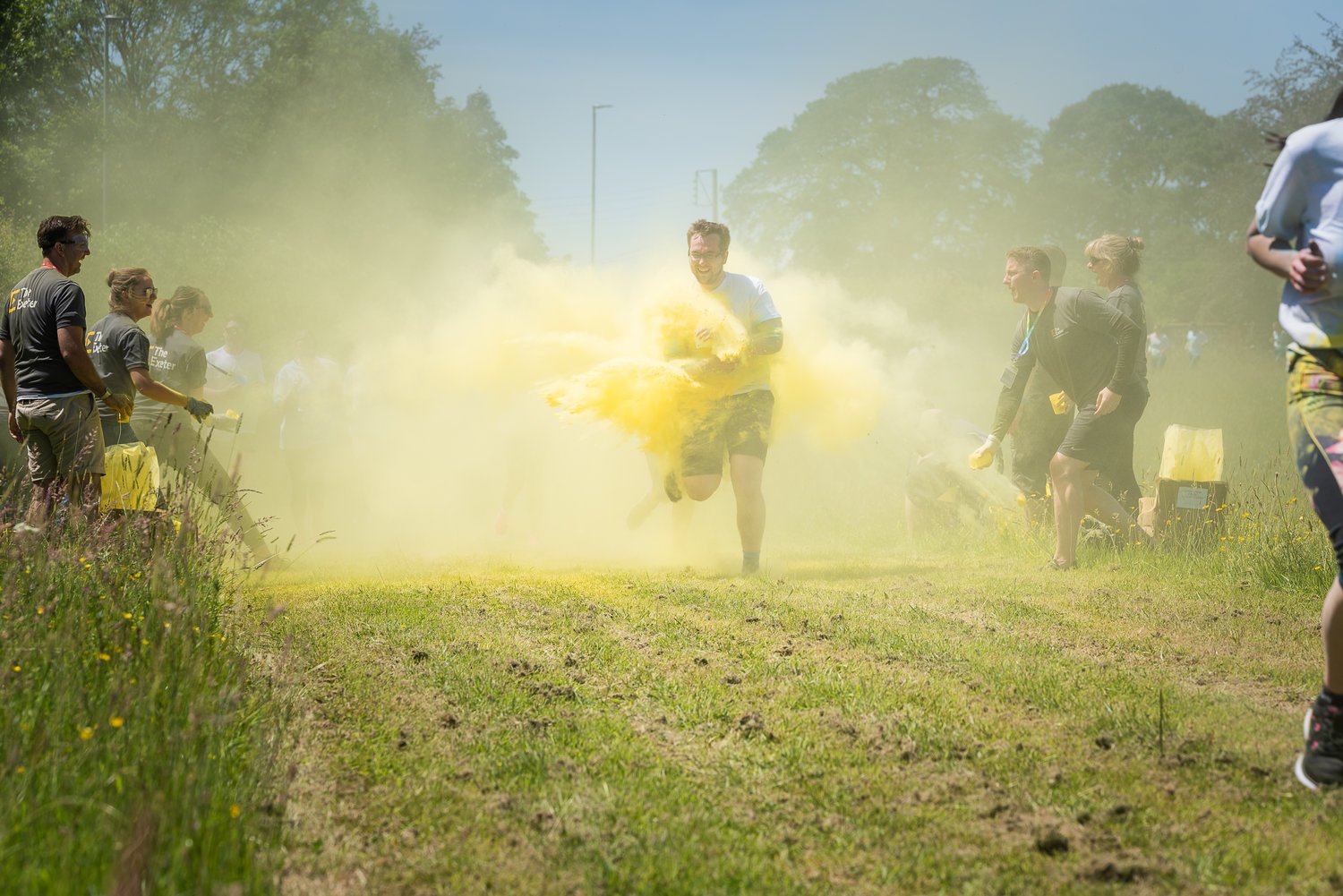 Professional photograph of a runner being sprayed with water as he runs across a field while spectators watch the sporting event