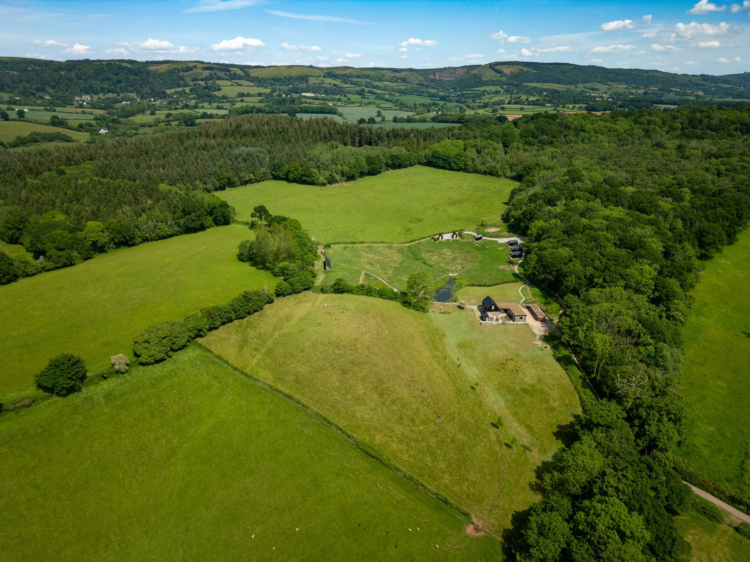 Drone photography of Somerset countryside with modern Eco House, fields, and surrounding woodland