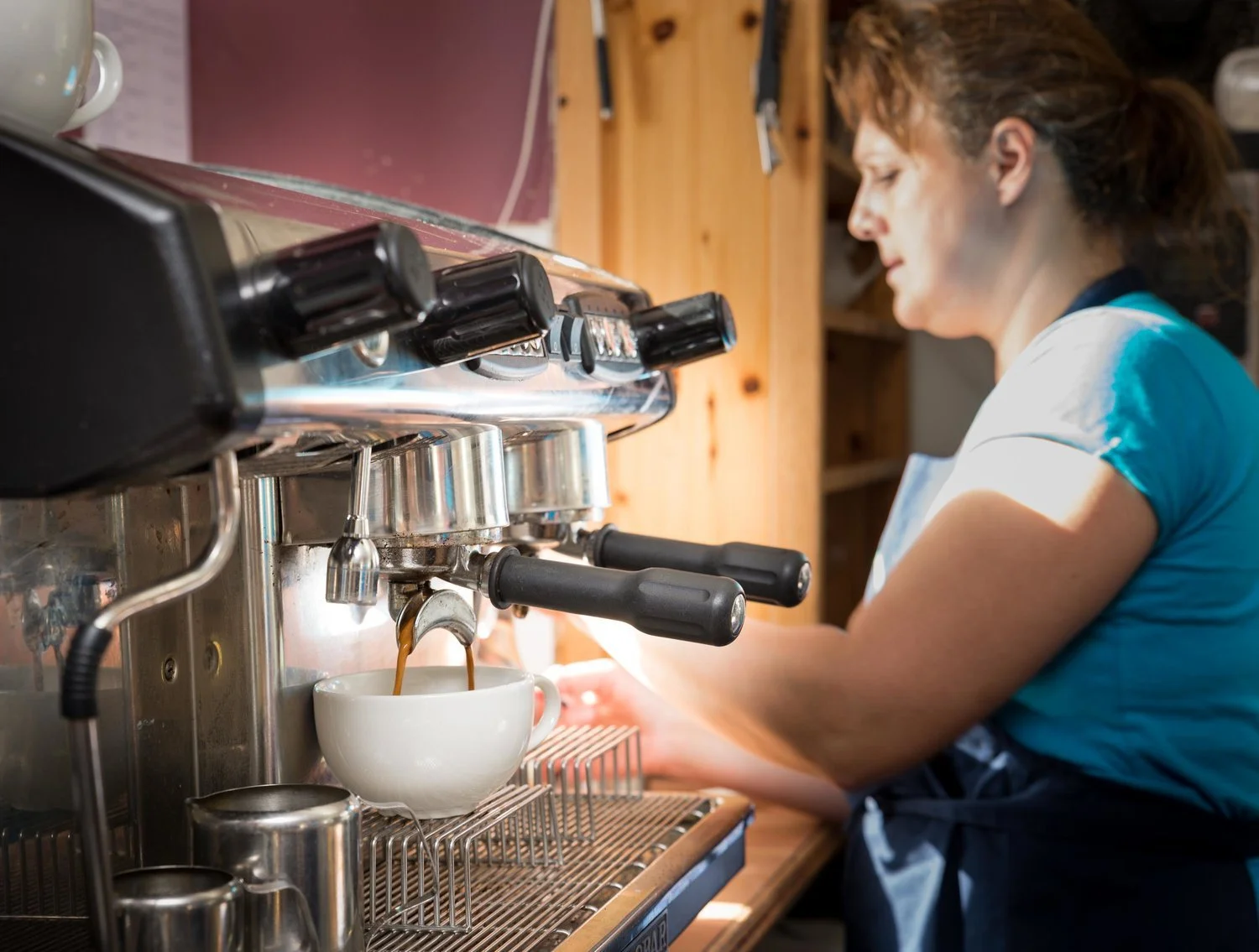 Artisan coffee moment captured in a lifestyle setting, featuring espresso in progress and a barista at work
