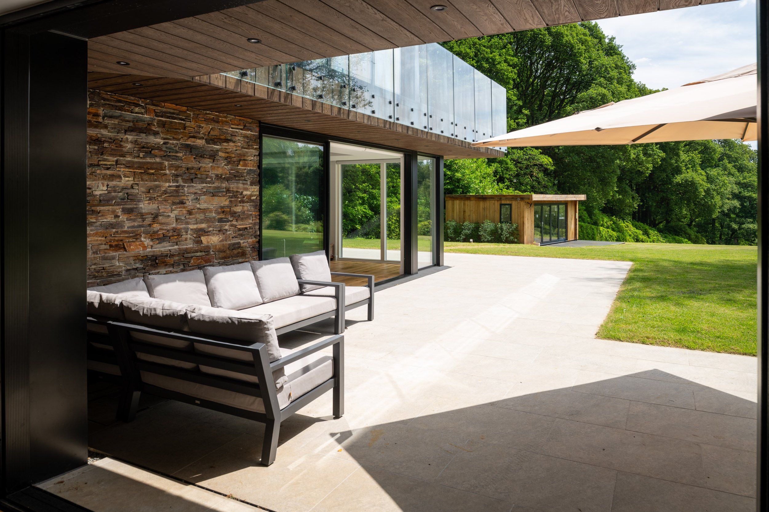 Modern outdoor patio with seating, glass balcony and landscaped garden, captured in a last-minute property photography shoot for estate agents, Airbnb and luxury property marketing