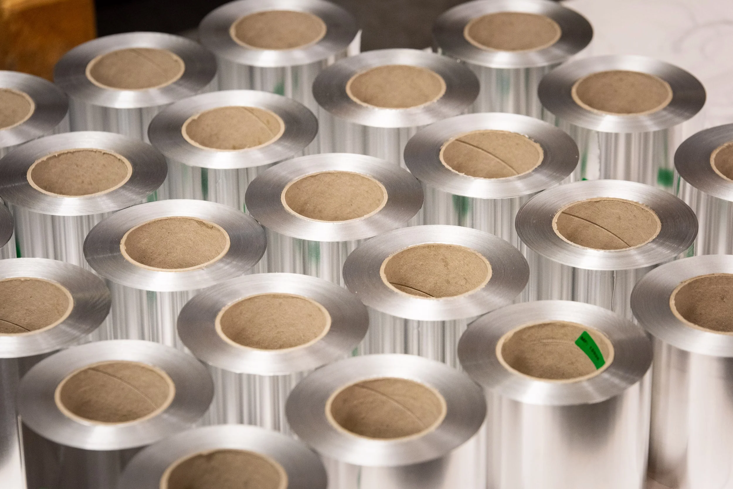 Close-up of multiple small aluminium foil rolls produced in bulk for industrial and commercial supply.