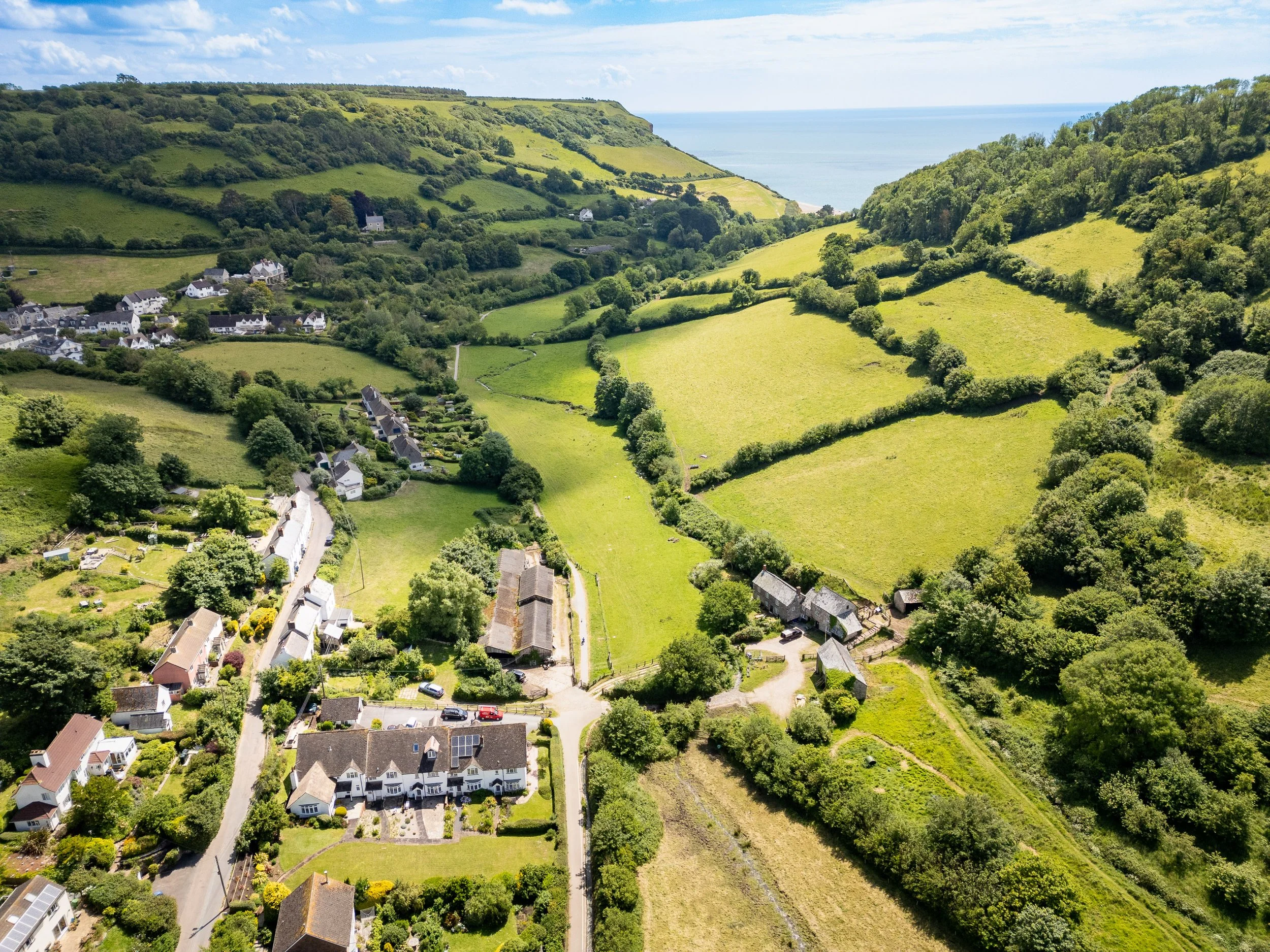 Drone photography of Somerset coastal village with countryside valley leading to the sea