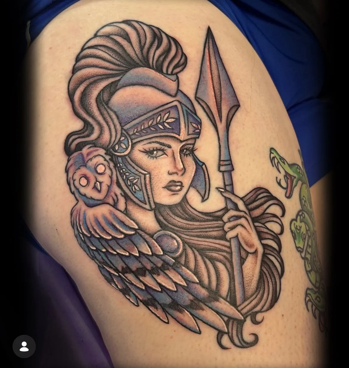 Tattoo of a warrior woman with long flowing hair, wearing a decorated helmet, holding a spear, with a snake nearby.