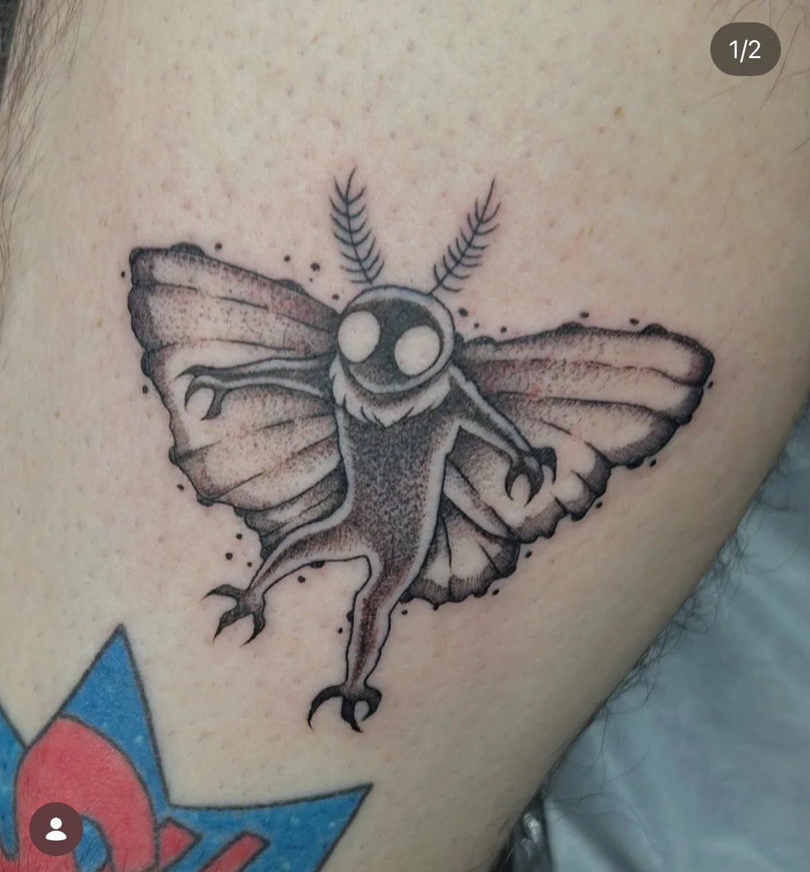 Tattoo of a moth with cartoonish eyes, detailed wings, and antennae on a person's skin. mothman