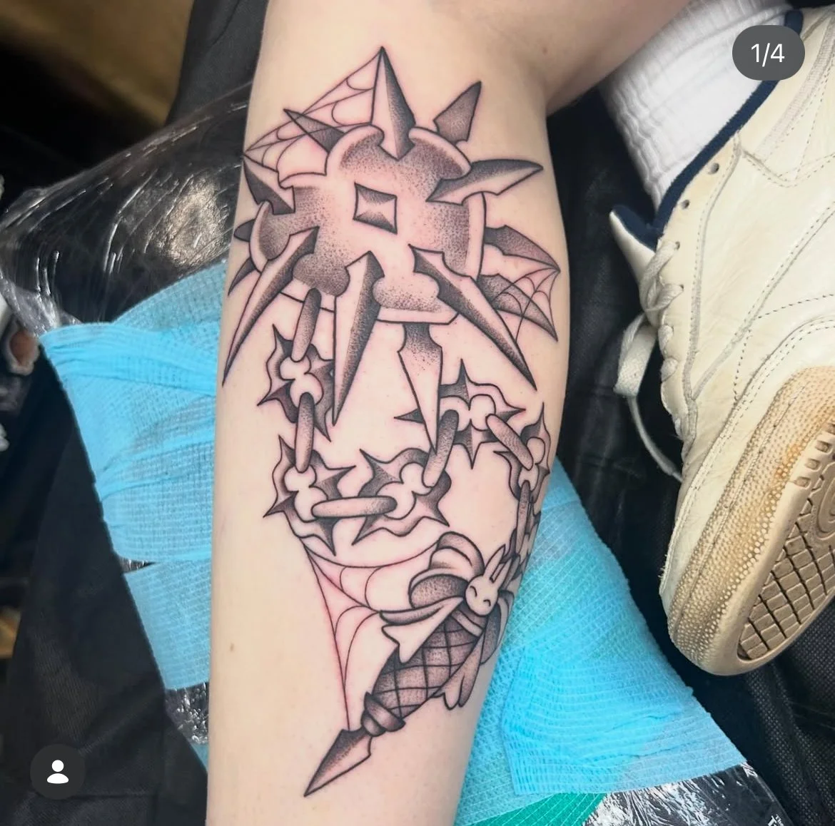 Tattoo of a dagger piercing through a thorny rose with spider web accents on a person's arm.