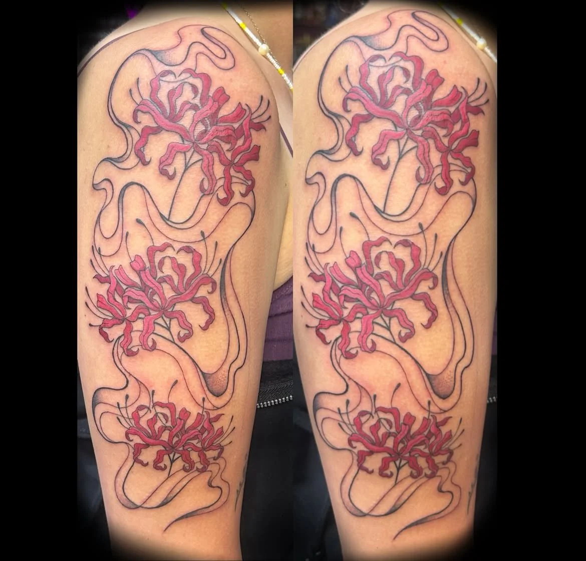 A tattoo of red spider lilies intertwined with black and grey line work on a person's upper arm.