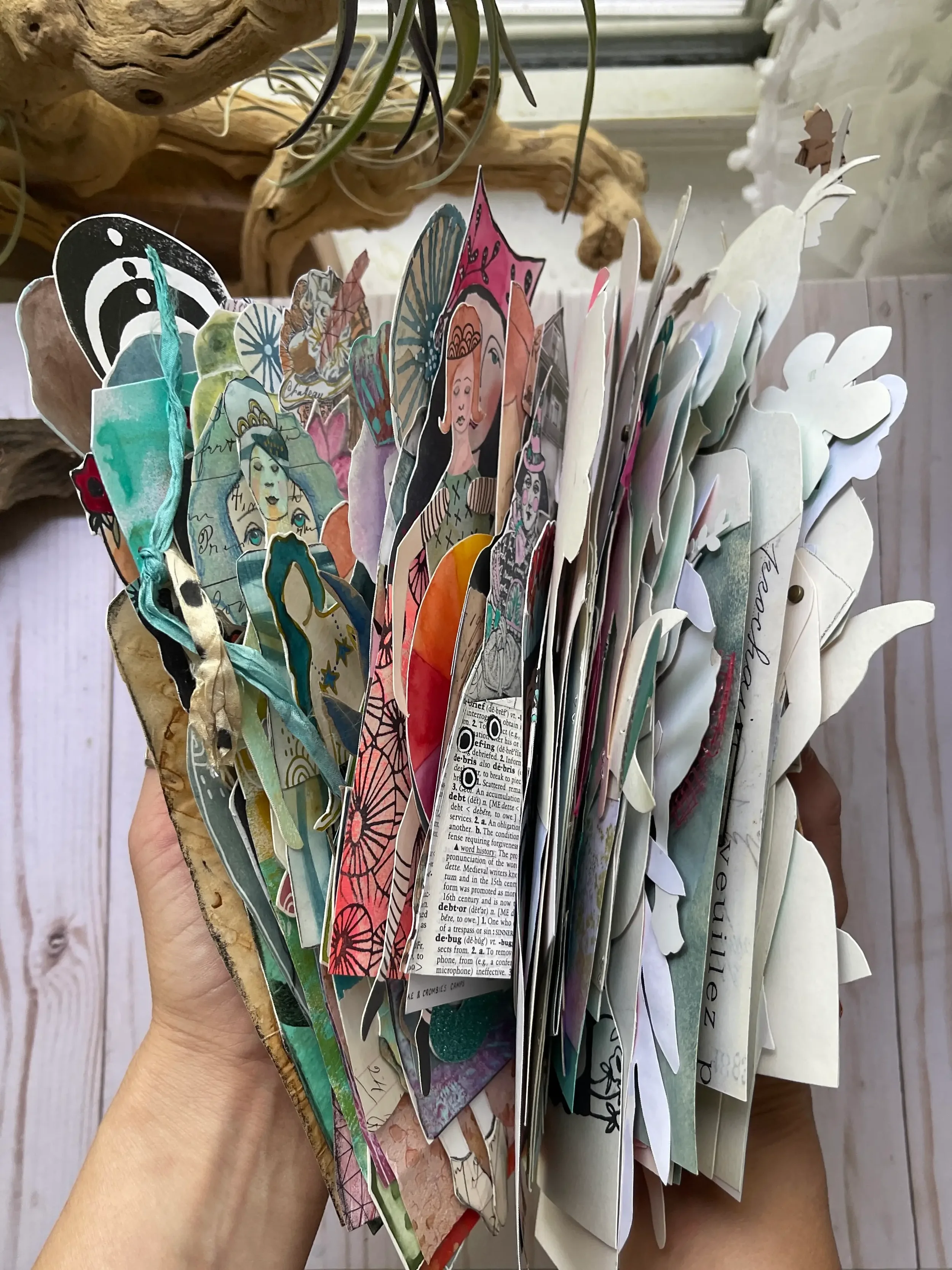 a wide variety of mixed media paper dolls held in the hand of megan quinlan