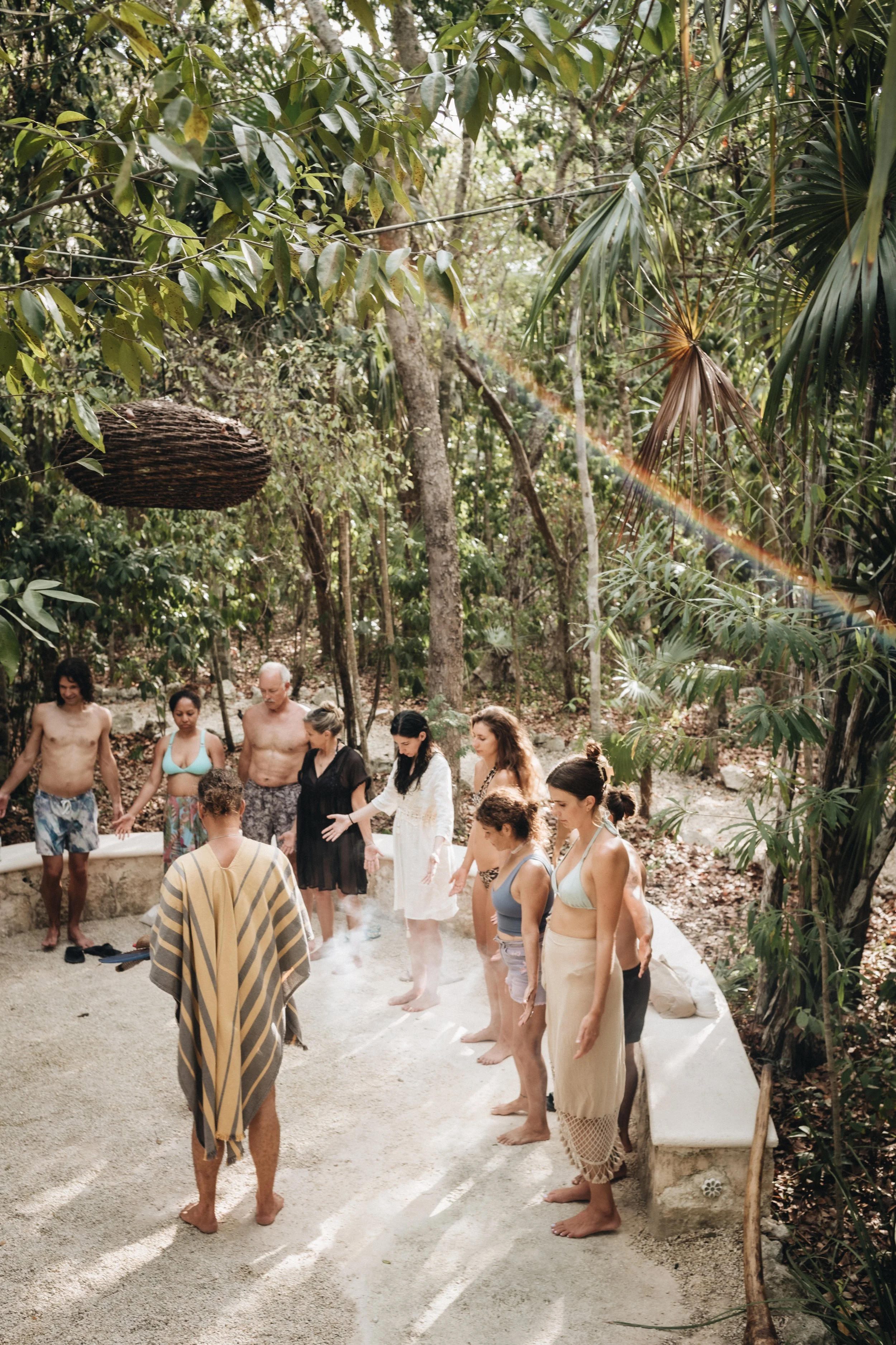 Group of people gathered barefoot for a wellness activity in a lush tropical forest