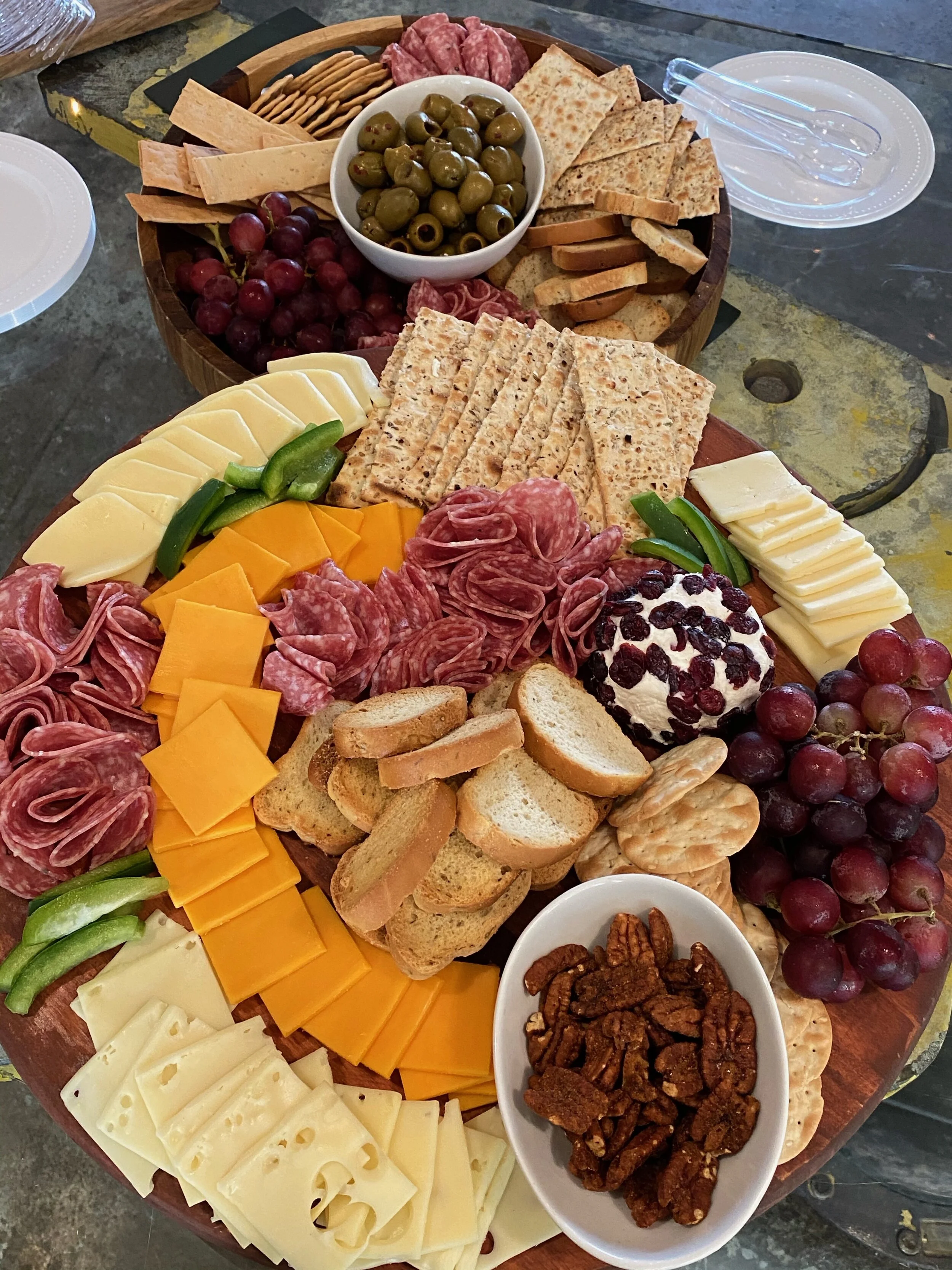 Charcuterie board with assorted cheeses, meats, crackers, olives, grapes, pecans, and cheese ball.
