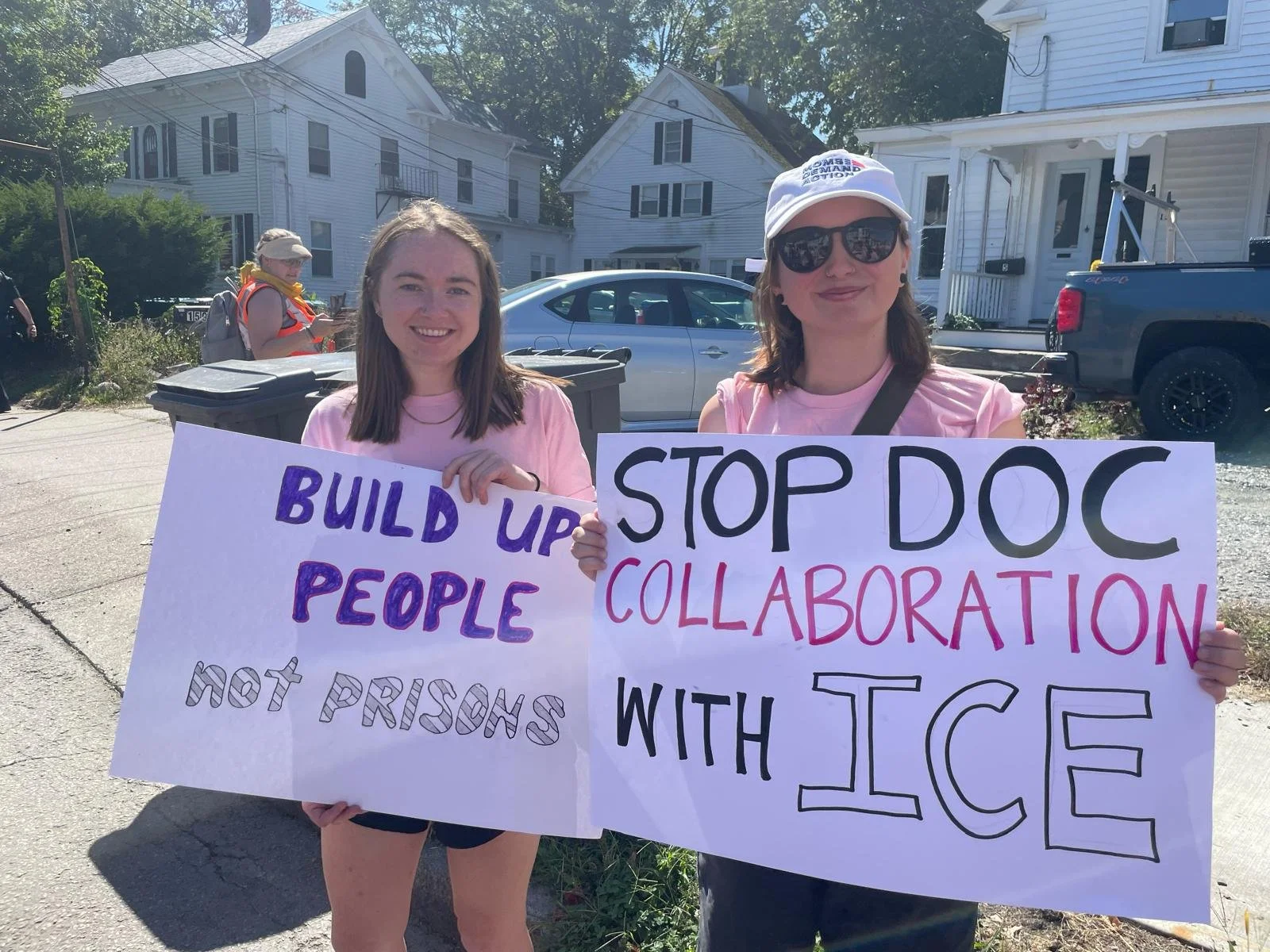 people holding signs reading build up people not prisons and stop DOC collaboration with ICE