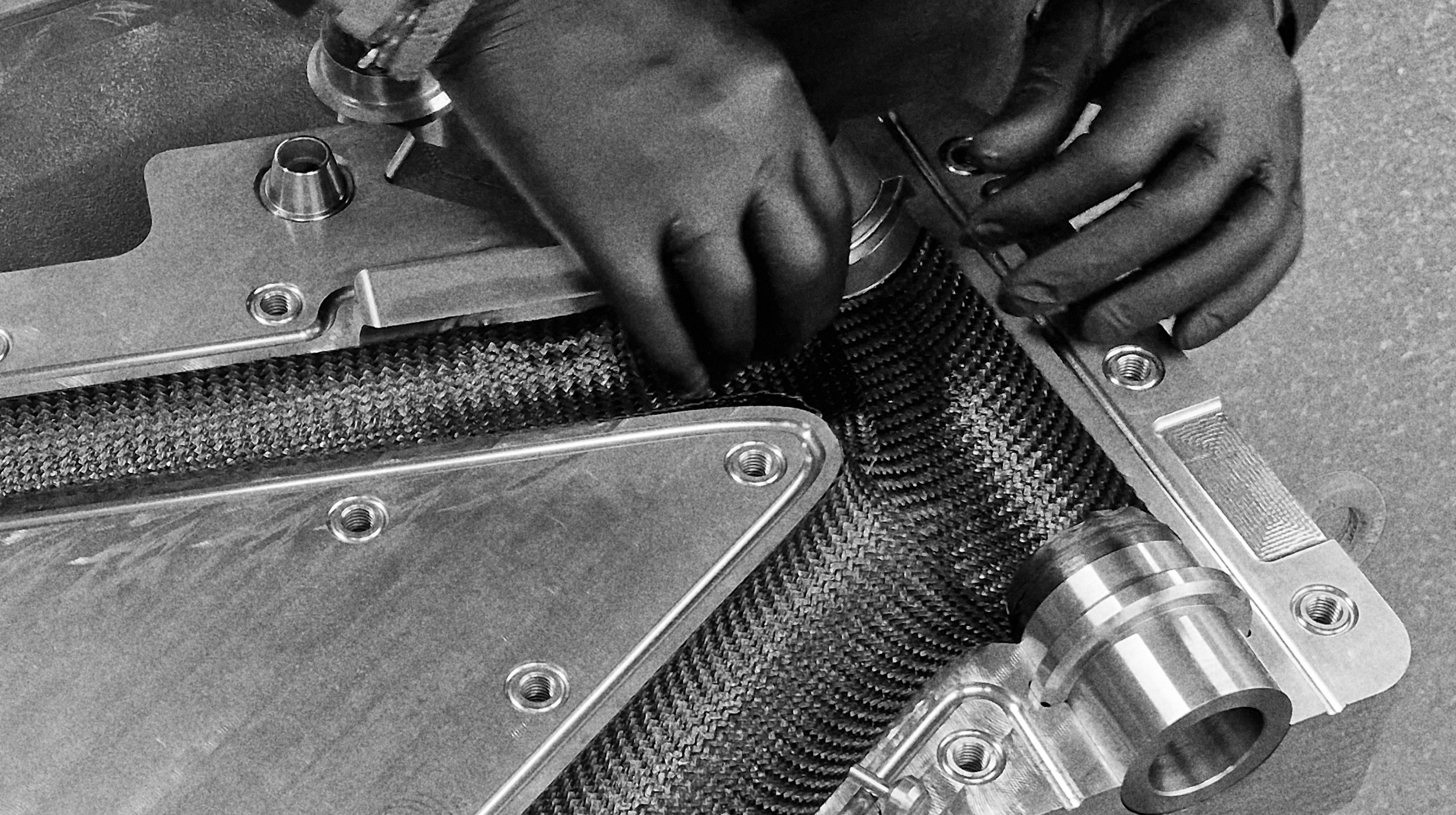 Hands preparing a carbon frame mould during EIDOLON manufacturing process.