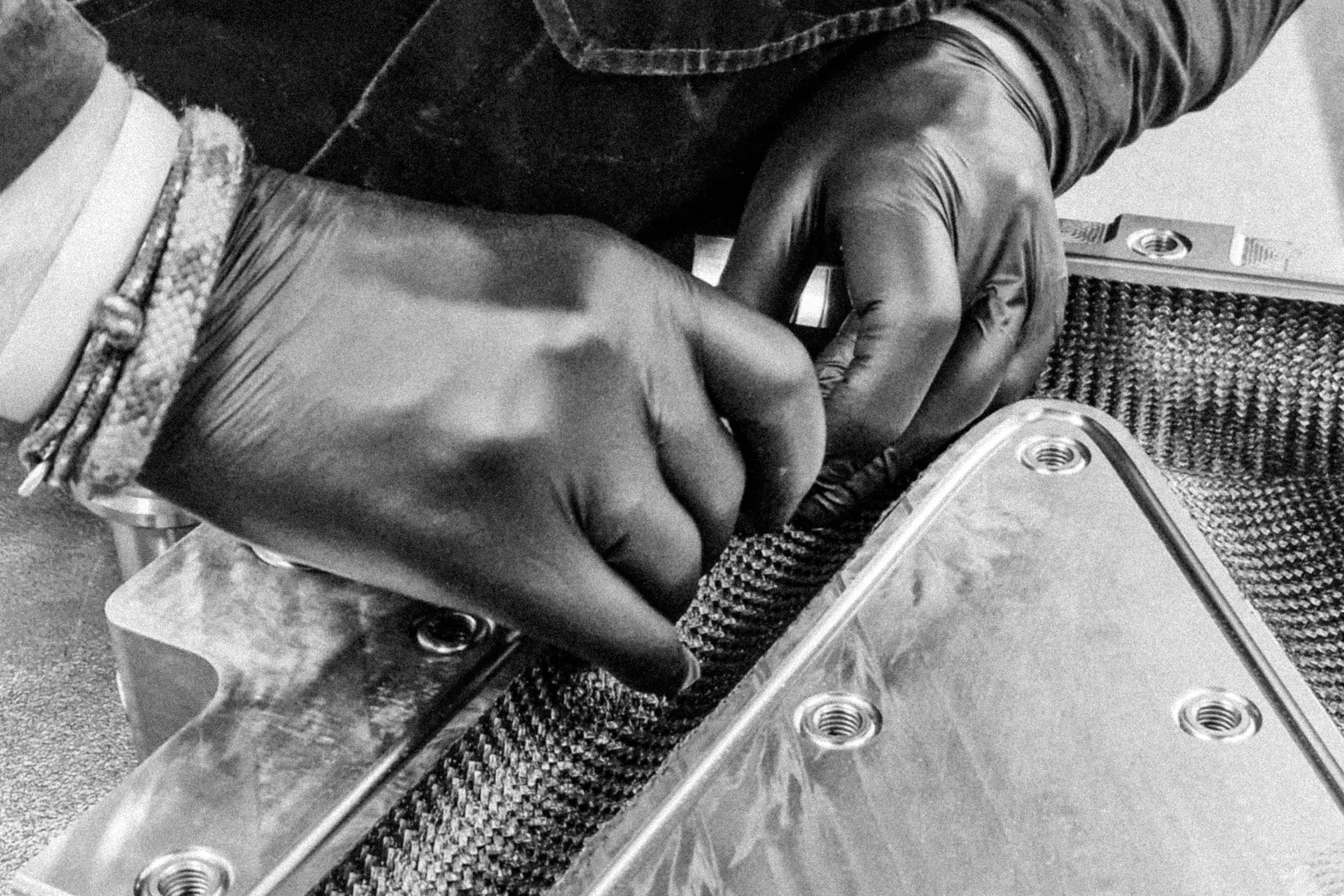 Hands preparing a carbon frame mould during EIDOLON manufacturing process.