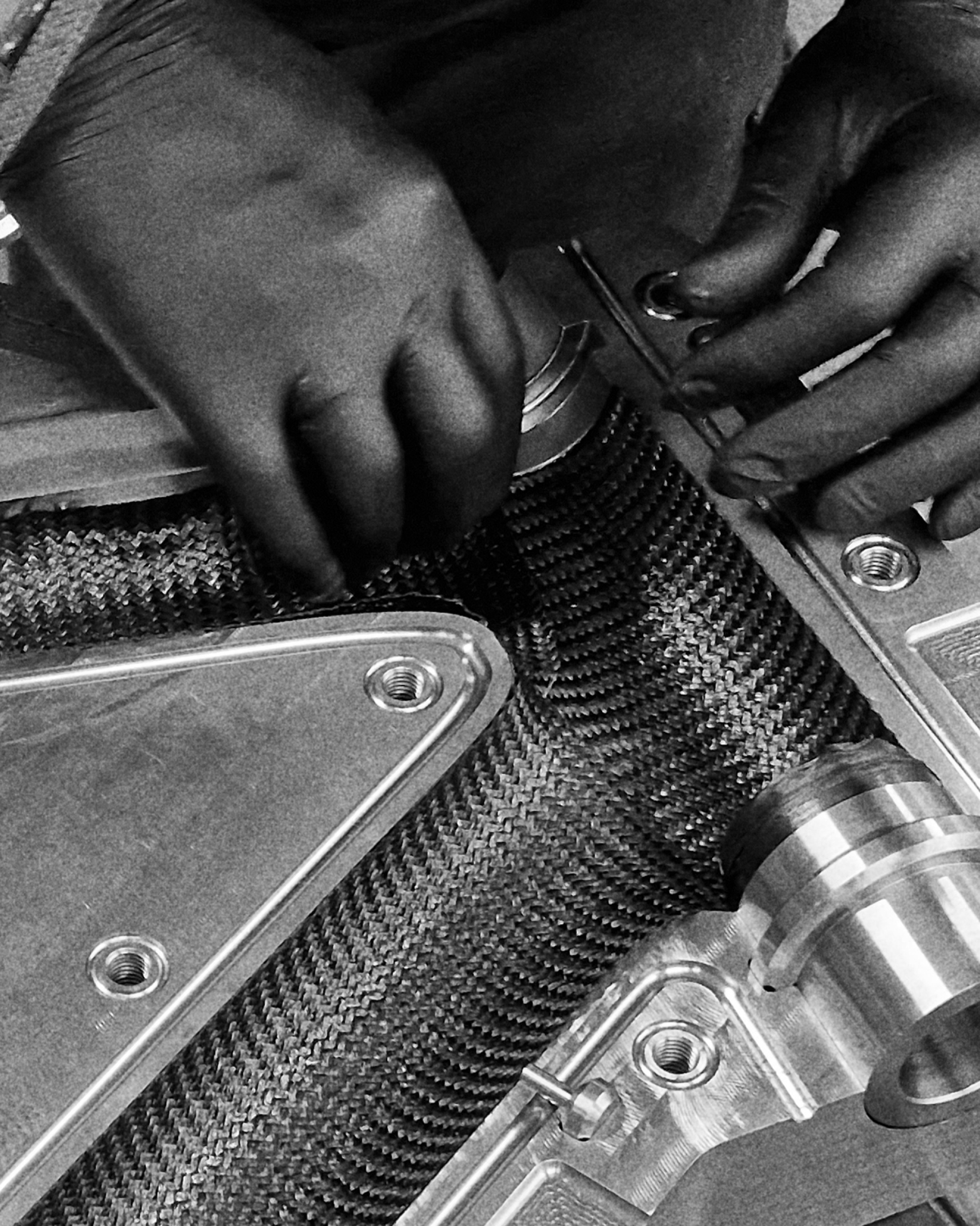 Hands preparing a carbon frame mould during EIDOLON manufacturing process.