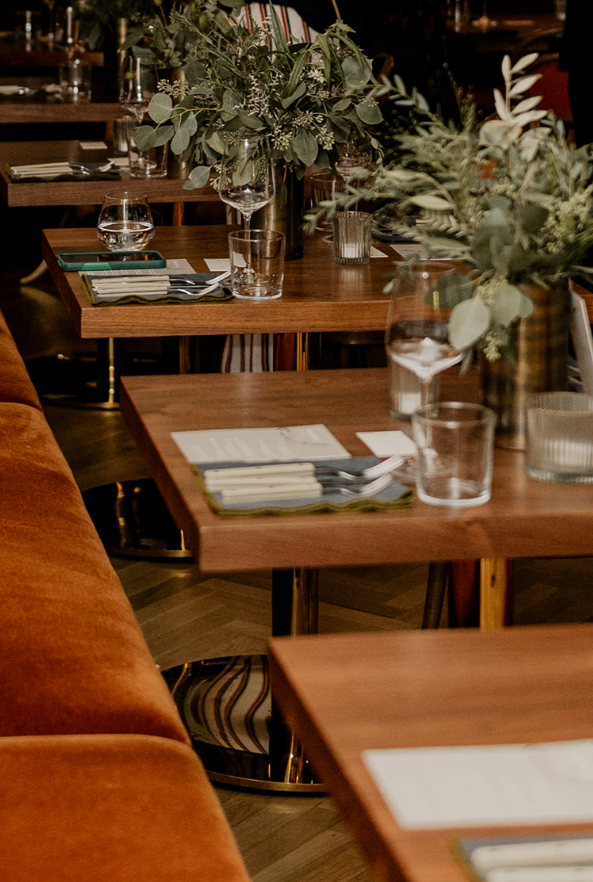 Elegant restaurant table setting with glassware, napkins, and floral centerpieces.