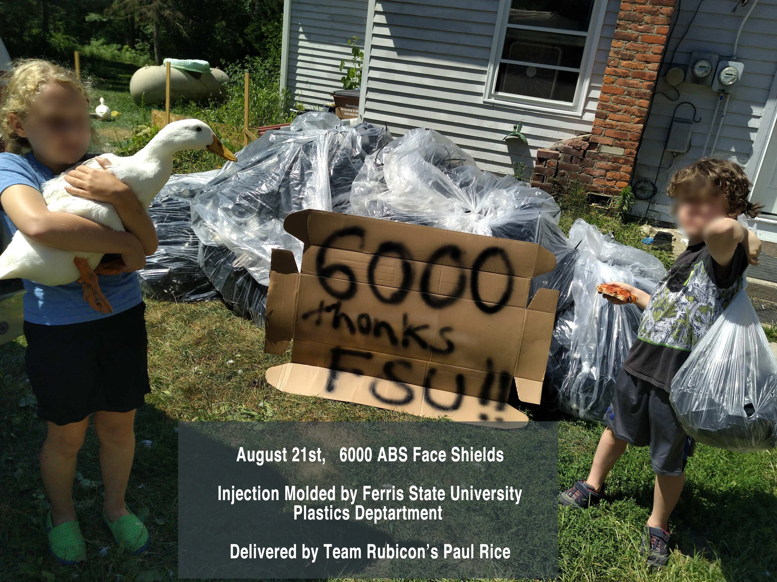 Two children outdoors, one holding a white duck, standing beside a large cardboard sign that reads '6000 thanks FSU!!'. Behind them, piles covered with black plastic, a house with siding, and a sign indicating a donation of 6000 ABS face shields.