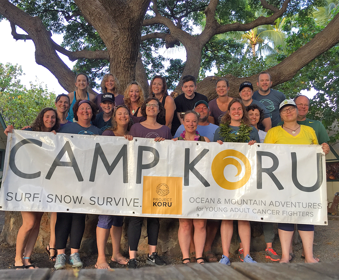 Calm and his group holding a sign that says "Camp Koru".