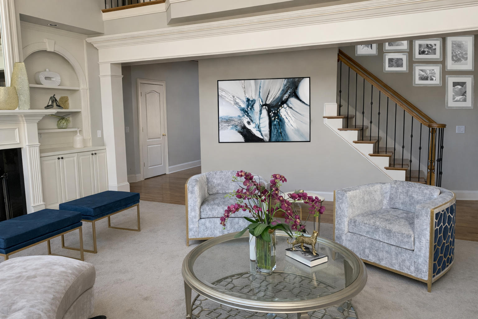 Cream arched built in shelving styled with gold flamingo sculptures, hydrangeas, and framed artwork beside a classic white fireplace mantel in a Hoschton Georgia home by Welcome Home Interiors