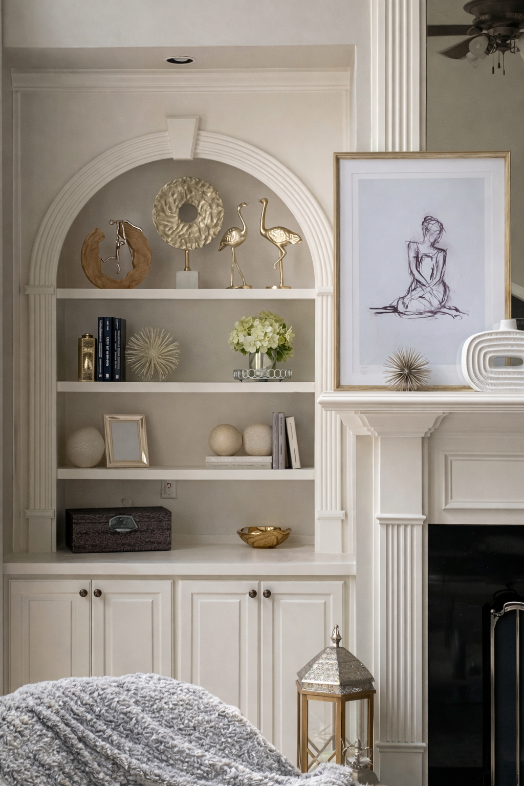Grand two story living room with abstract art above seating area, blue velvet benches, glass coffee table, and staircase gallery wall designed by Welcome Home Interiors in Hoschton Georgia