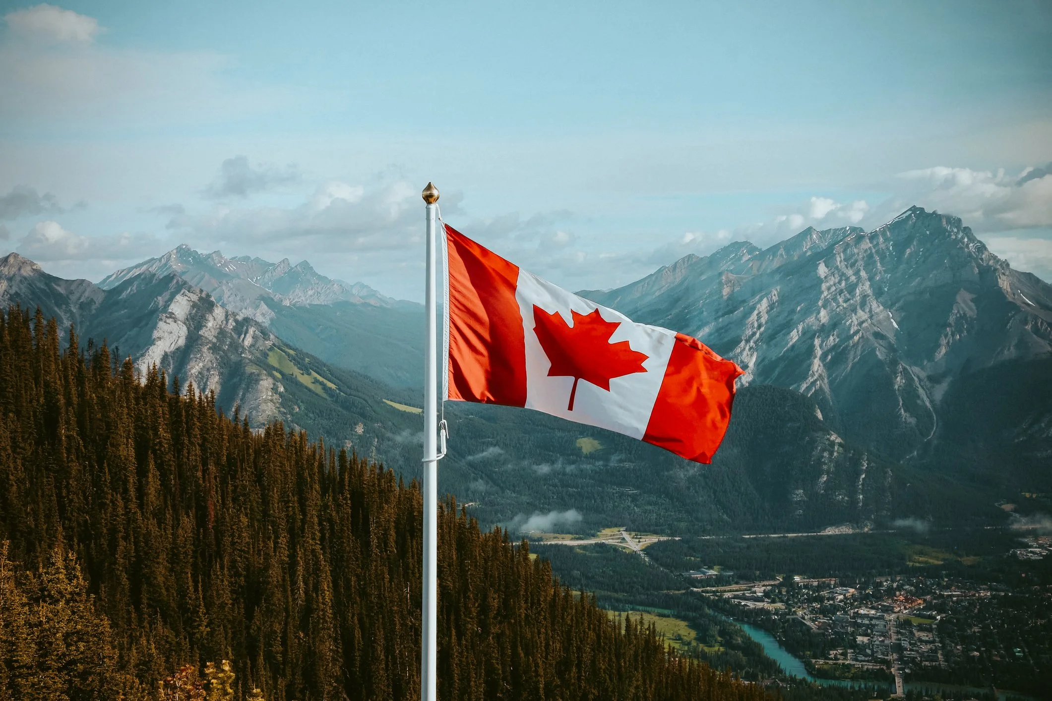 Canadian Flag blowing in the wind with the background of mountains