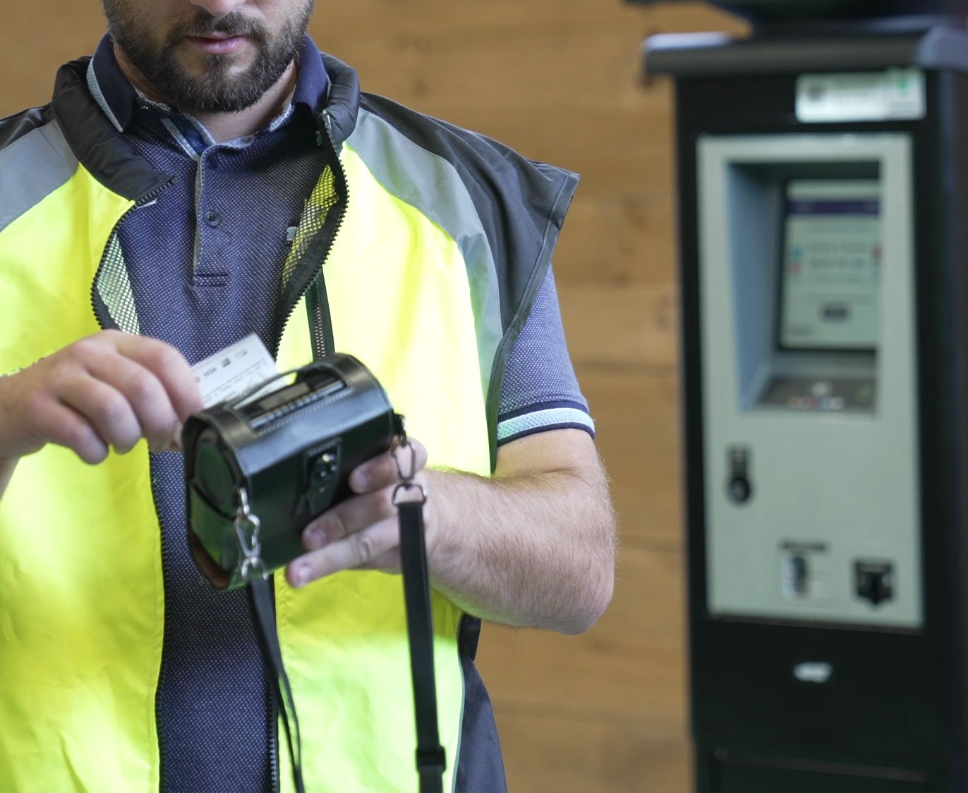 Parking enforcement officer using a handheld ticket printer beside a parking meter