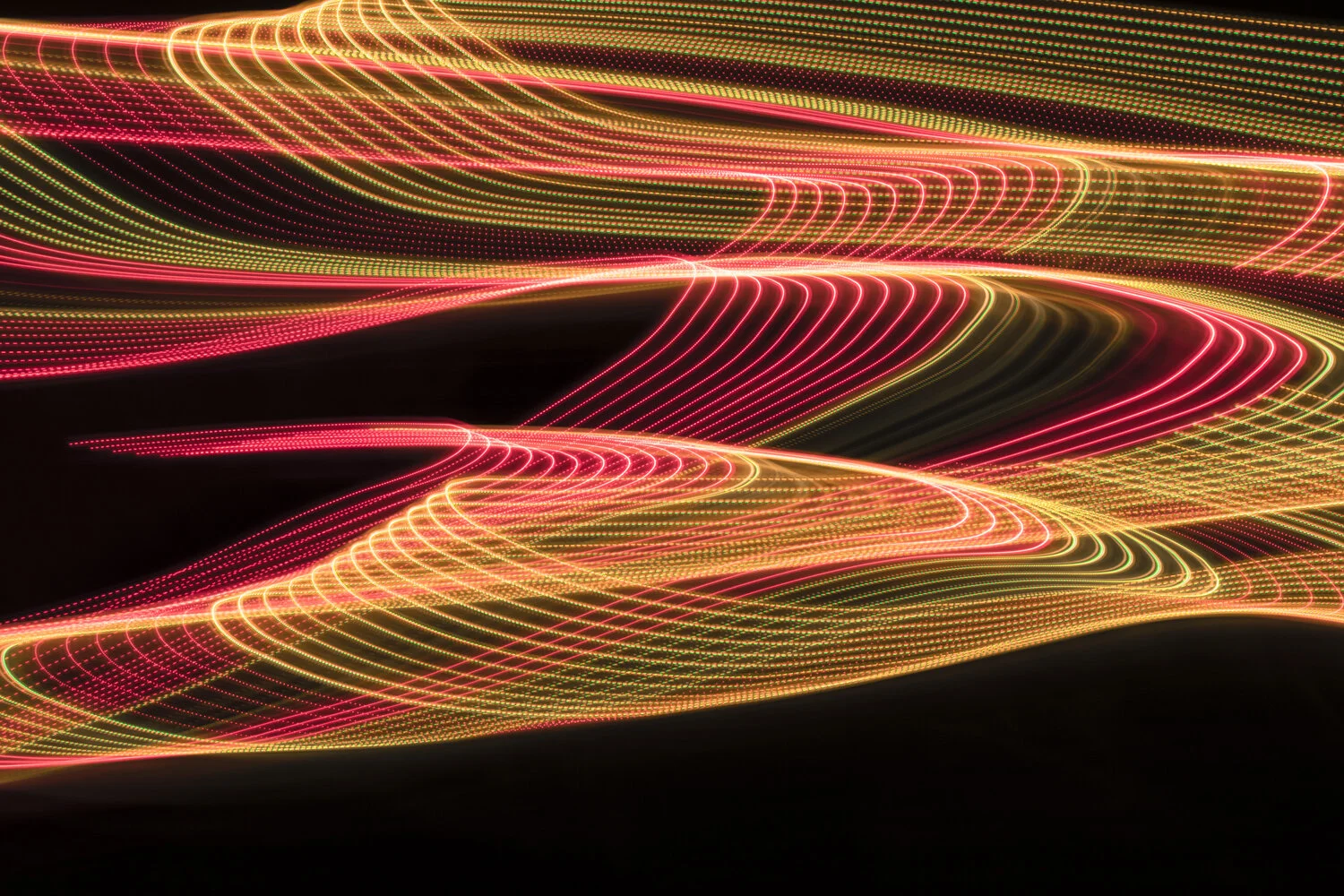 Colorful streaks of neon lights in red, yellow, and green, creating swirling abstract light trails against a black background.