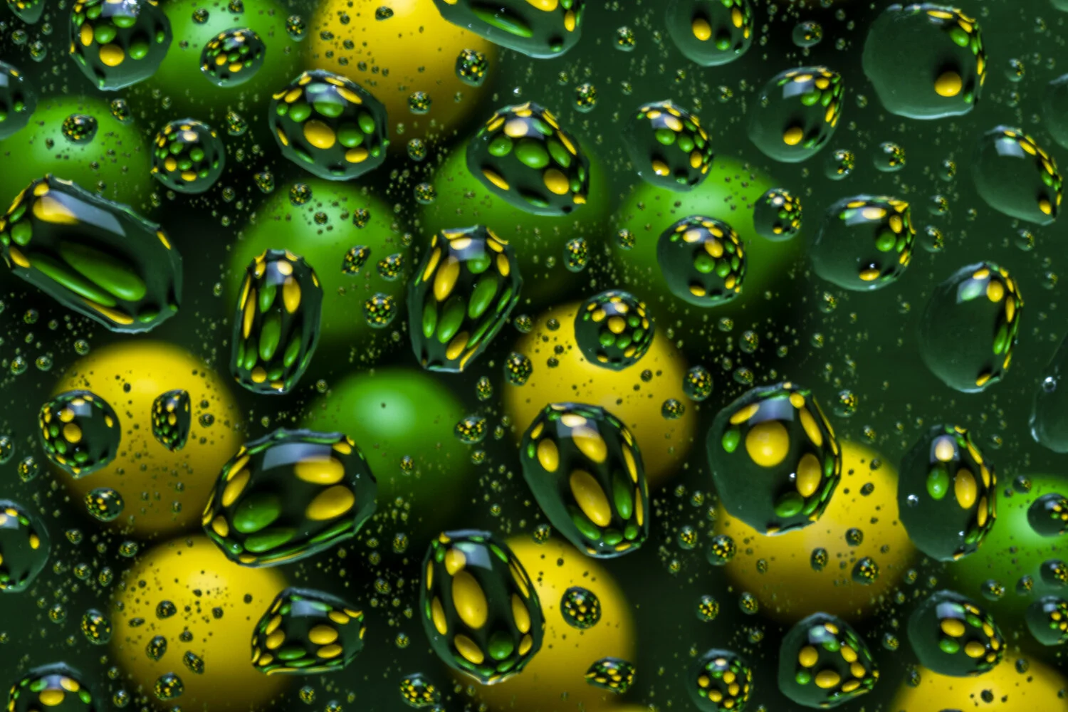 Close-up view of green and yellow marbles submerged in oil, creating a pattern of floating spheres and bubbles.