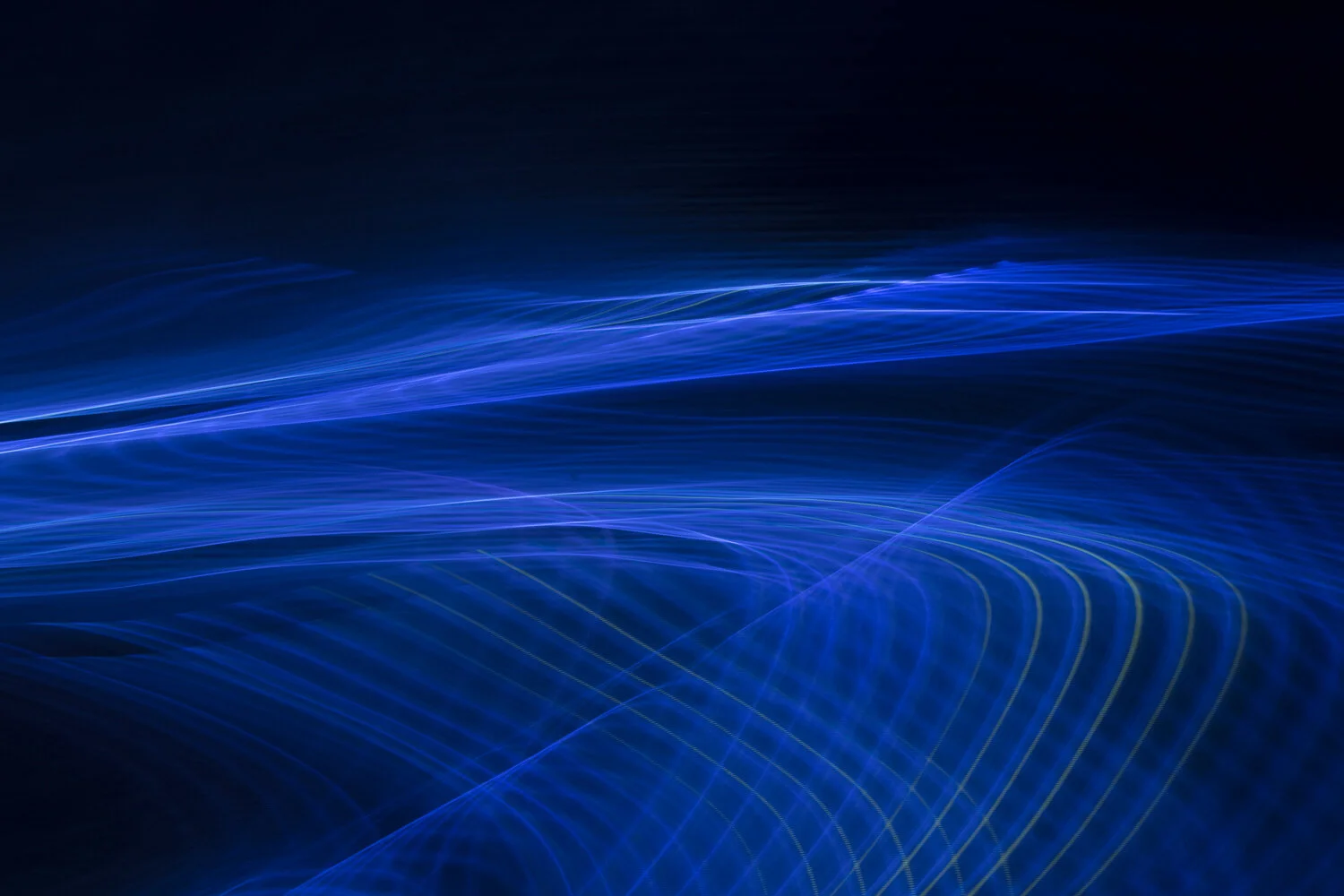 Abstract image of glowing blue light trails flowing across a dark background.