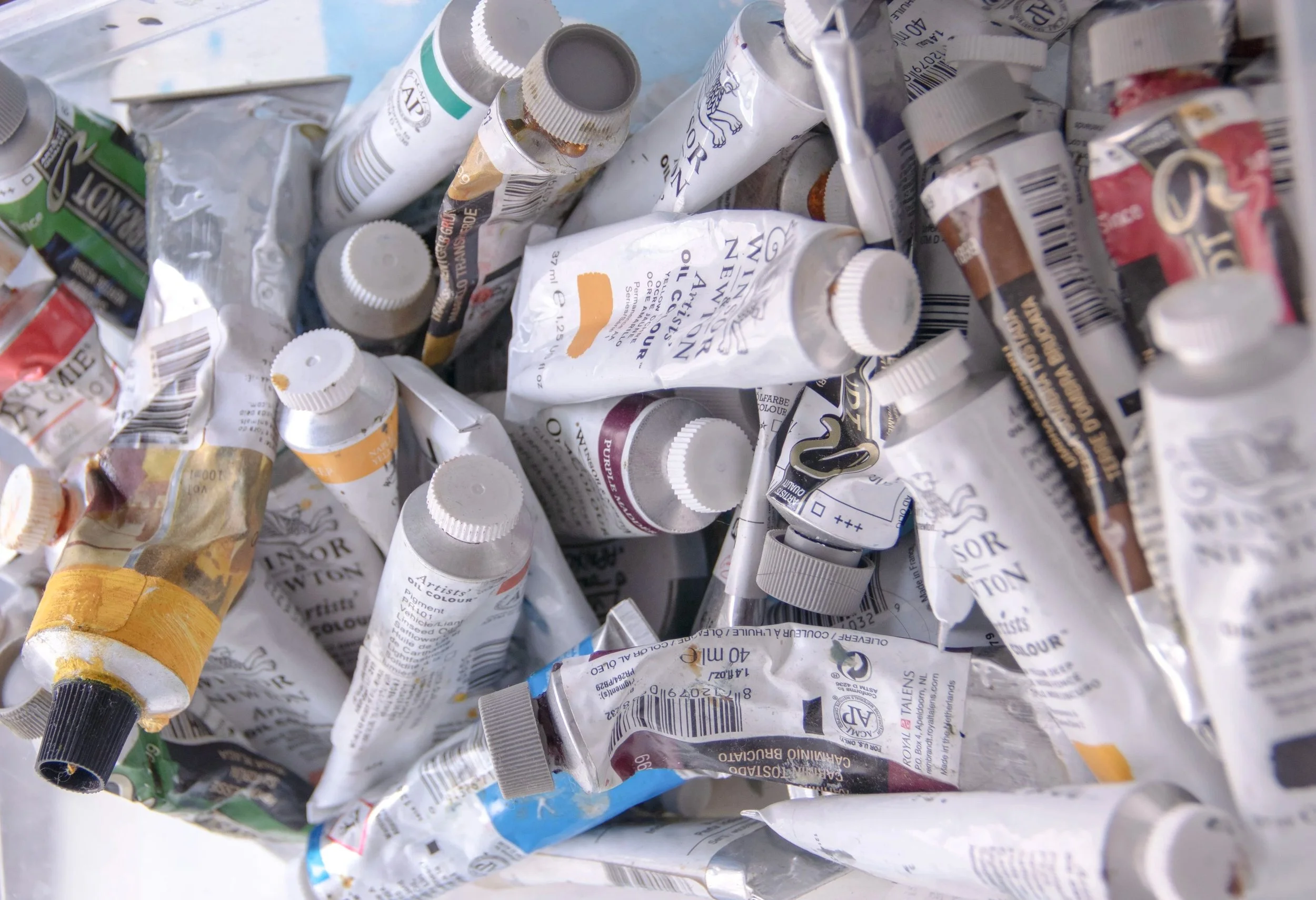 Tubos de tinta óleo de artistas em várias cores, empilhados e dispersos.