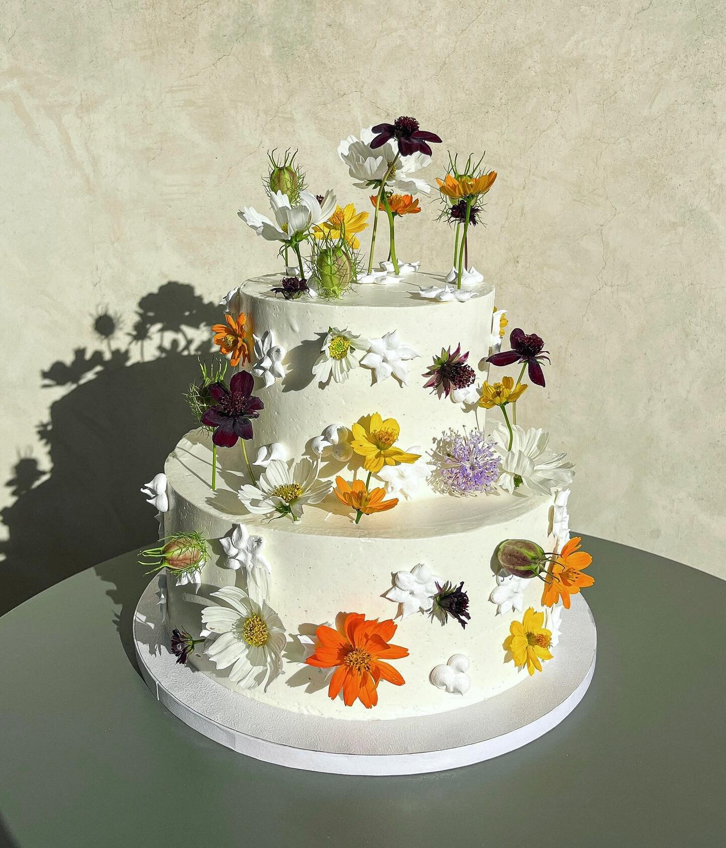 Jenna &amp; Eamon&rsquo;s cake from last month @casa_cody 🤍🌈🌸🌿🌼studded with meringue flowers and real blooms🌞🌞🌞