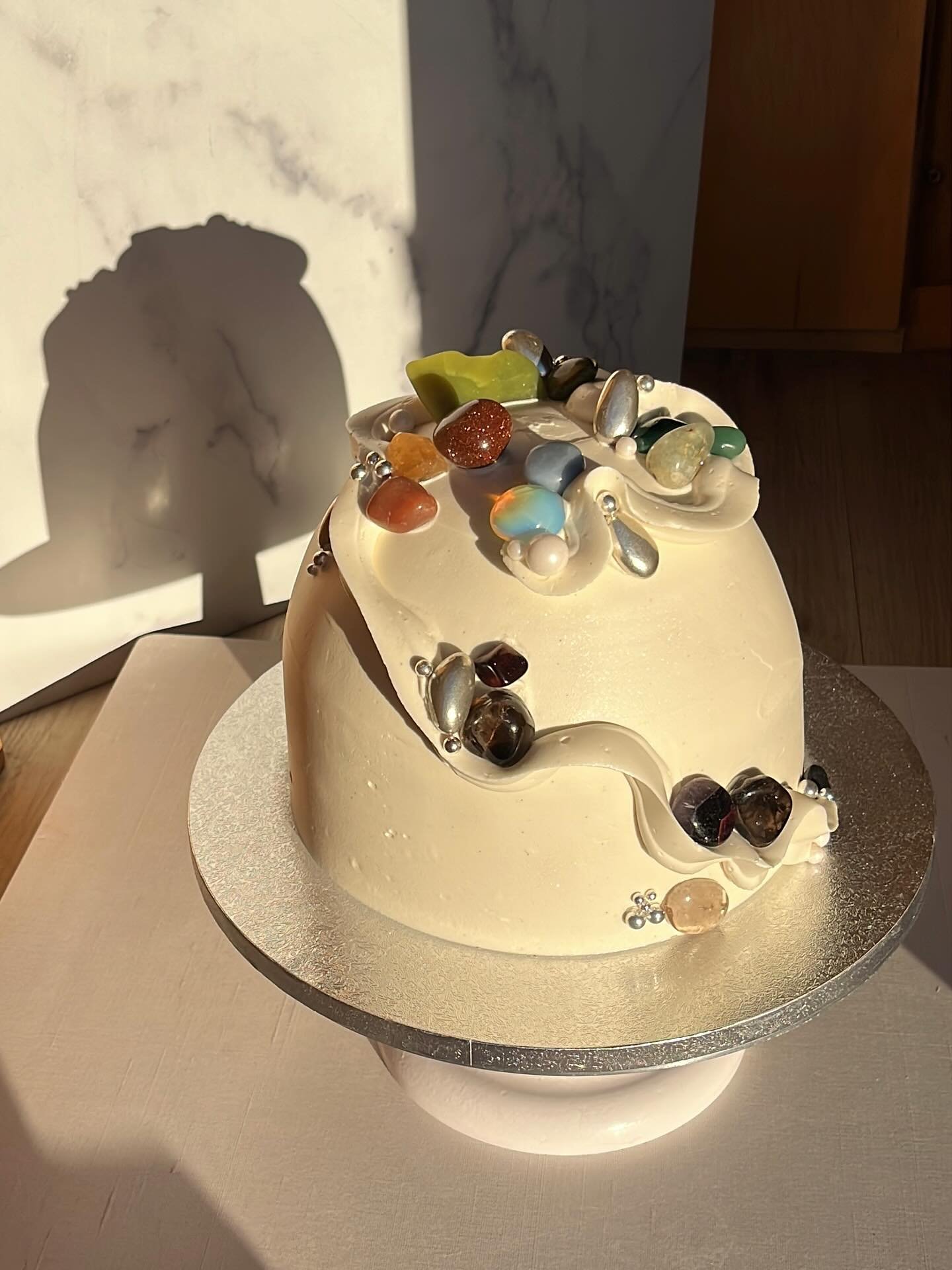 a really special dome for @theshootoutsociety ✨🪐adorned with semi precious stones, pooling in like-tones, nestled in their buttercream stream🌈

#quartz #malachite #tigerseye #PICNICbakedgoods #pioneertown #palmsprings #weddingcake #SMBC #baker #opa