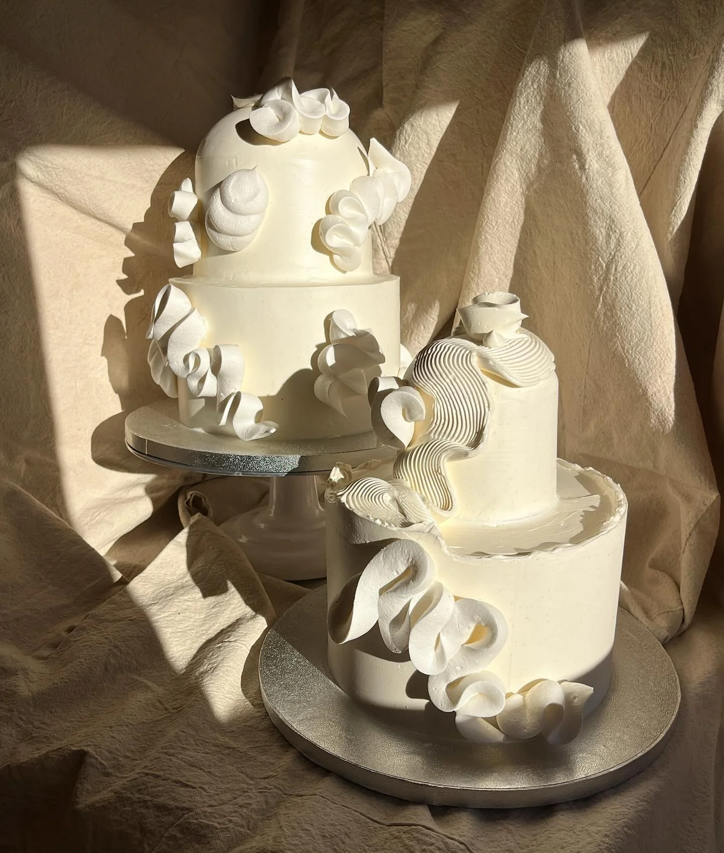 morning light kissing two sister cakes from last weekend before they got botanical and went to their venues🐚🦢🪽🤍the monochromatic simplicity just sooooooothes my being🧘🏼 

#domecake #meringue #squiggles #PICNICbakedgoods #pioneertown