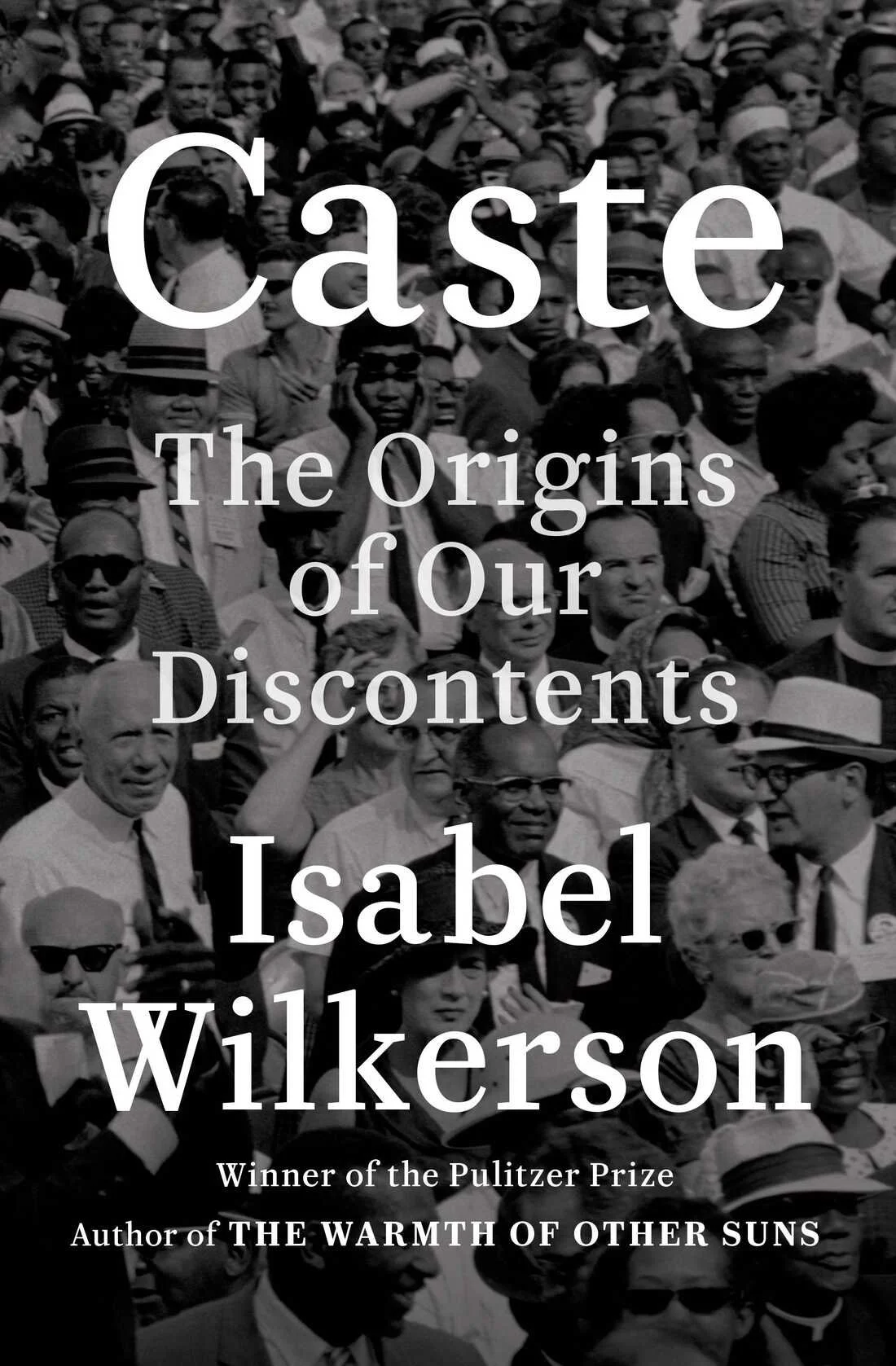 Cover of the book 'Caste: The Origins of Our Discontents' by Isabel Wilkerson, featuring a black-and-white photo of a large, diverse crowd of people from the 1960s era. The text highlights Wilkerson as a Pulitzer Prize winner and author of 'The Warmt