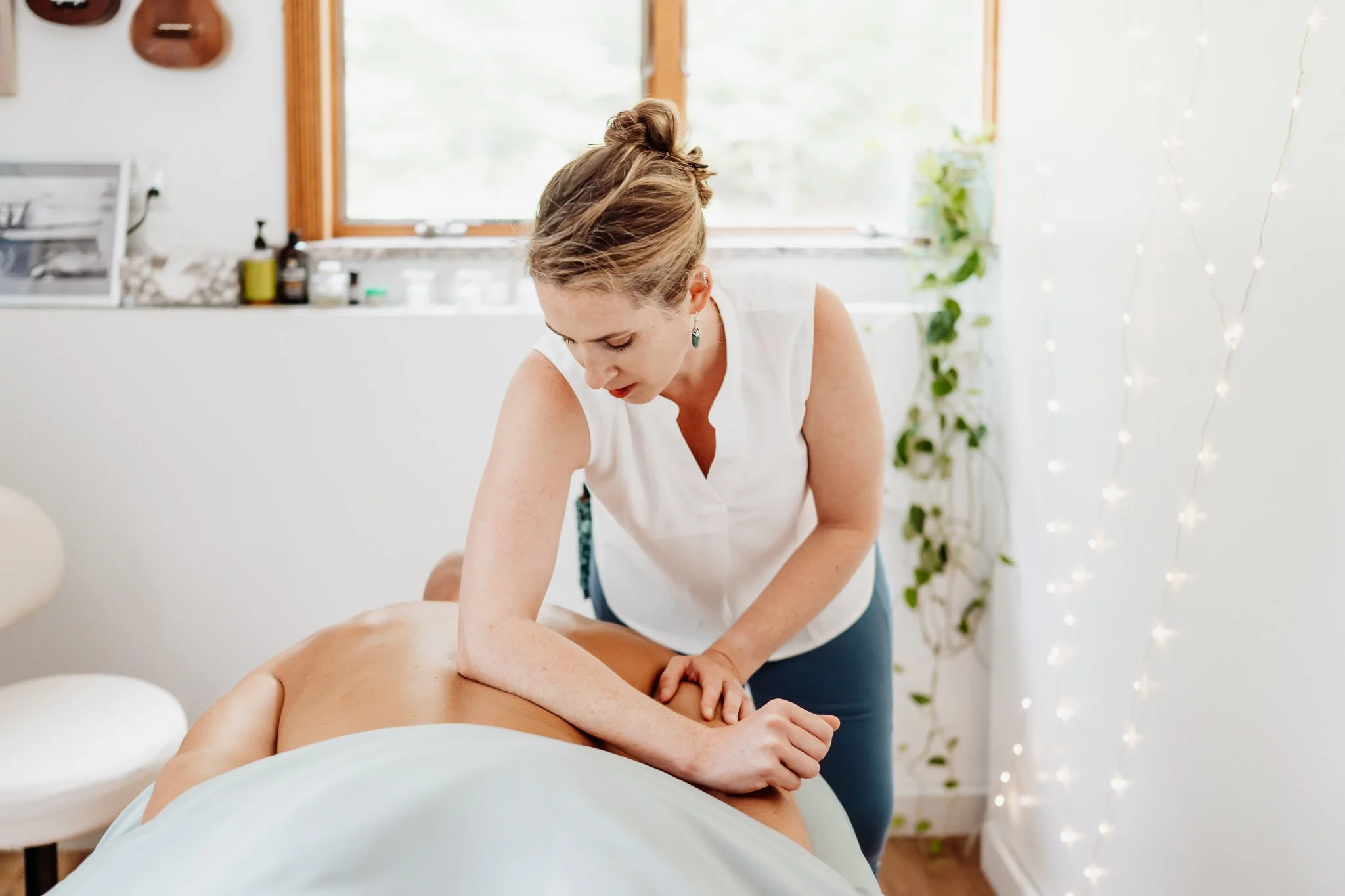 Massage therapist performing deep tissue massage to relieve low back pain in serene coastal Maine office space